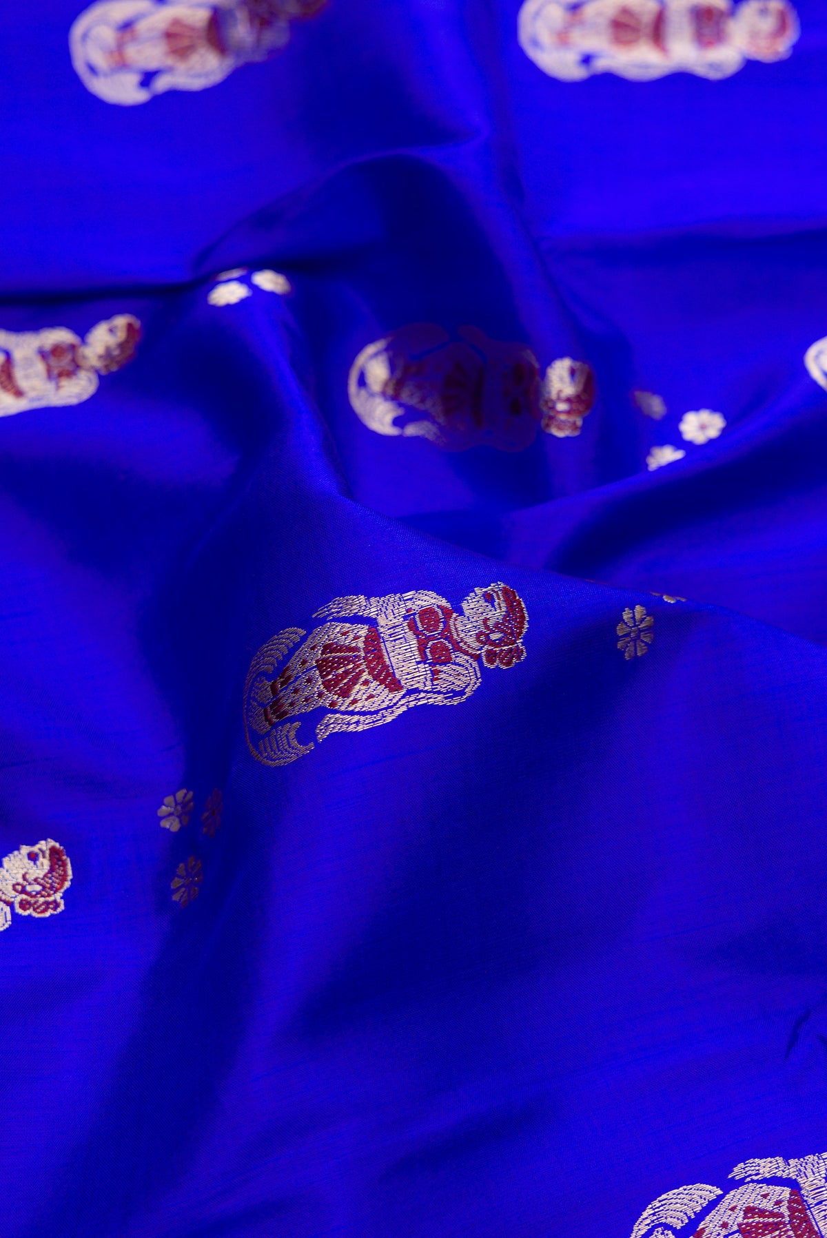 Close up of Pure Silk Royal Blue Baluchari Saree with Zari And Thread Butta on the body and Fancy Border.  displaying folds