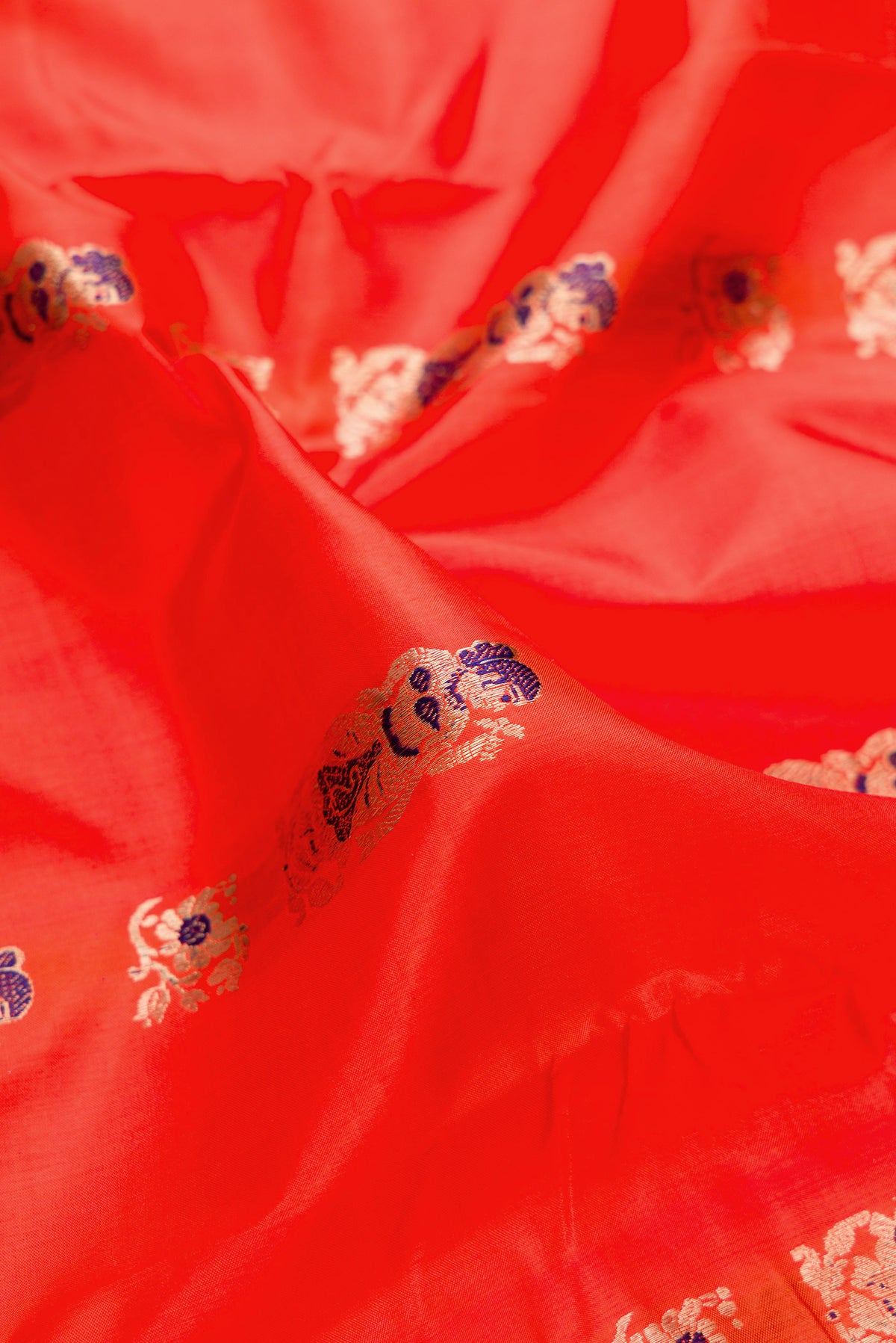 Close up of Pure Silk Orange Baluchari Saree with Zari And Thread Butta on the body and Fancy Border.  displaying folds