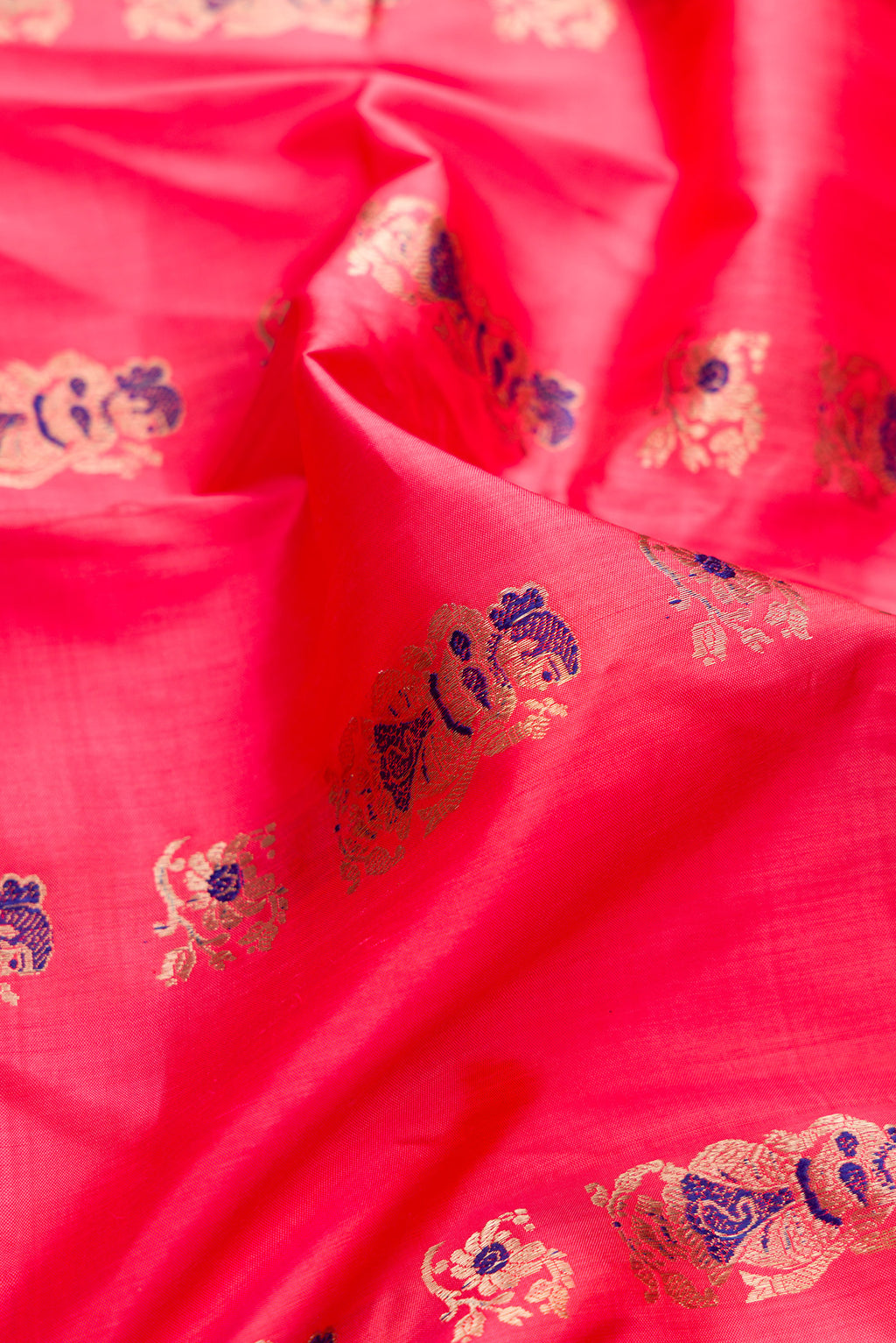 Close up of Pure Silk Coral Baluchari Saree with Zari And Thread Butta on the body and Fancy Border.  displaying folds