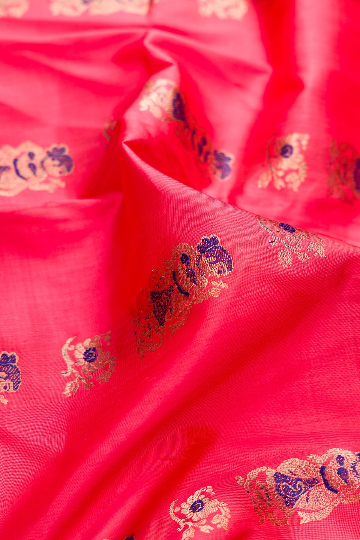 Close up of Pure Silk Coral Baluchari Saree with Zari And Thread Butta on the body and Fancy Border.  displaying folds