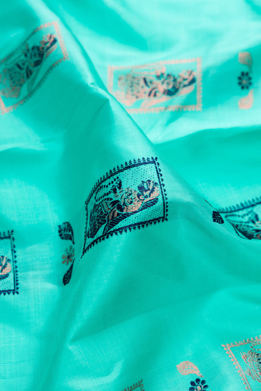 Close up of Pure Silk Turquoise Baluchari Saree with Zari And Thread Butta on the body and Fancy Border.  displaying folds