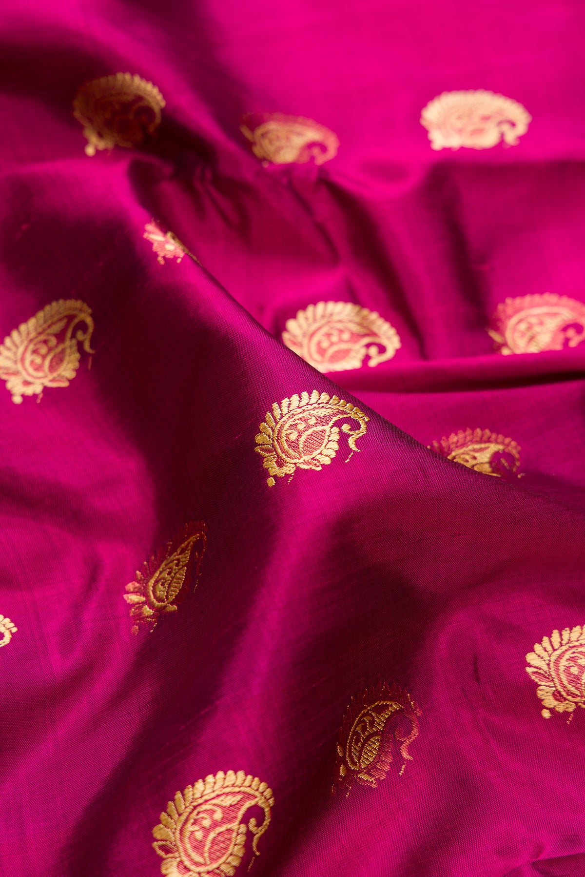 Close up of Pure Silk Magenta Dual Tone Baluchari Saree with Zari And Thread Butta on the body and Fancy Border.  displaying folds