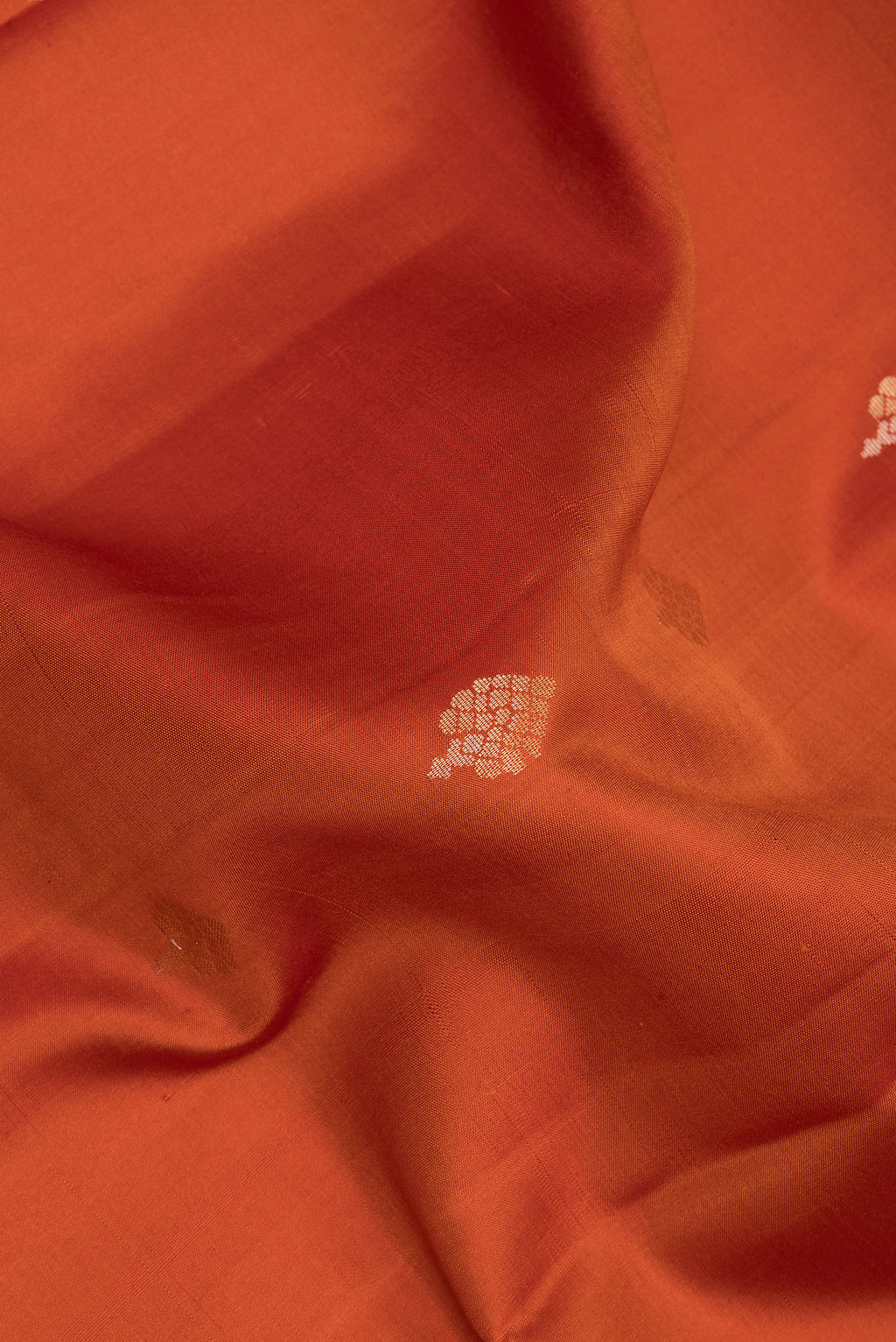 Close up of Pure Silk Rust Dual Tone Soft Saree with Zari Butta on the body and Zari Border.  displaying folds