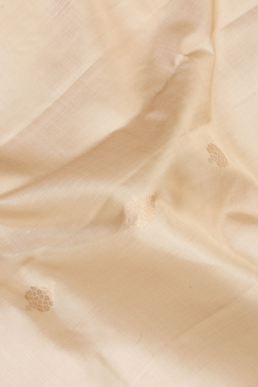 Close up of Pure Silk Beige Dual Tone Soft Saree with Zari Butta on the body and Zari Border.  displaying folds