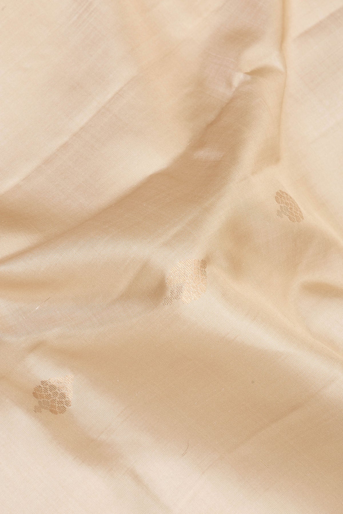 Close up of Pure Silk Beige Dual Tone Soft Saree with Zari Butta on the body and Zari Border.  displaying folds