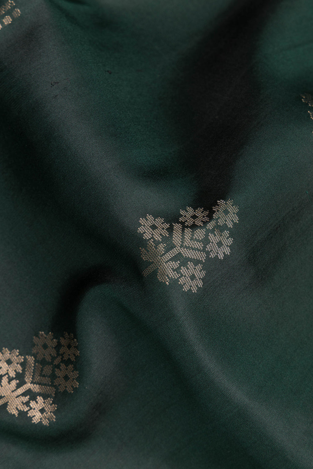 Close up of Pure Silk Bottle Green Soft Saree with Zari Butta on the body and Zari Border.  displaying folds