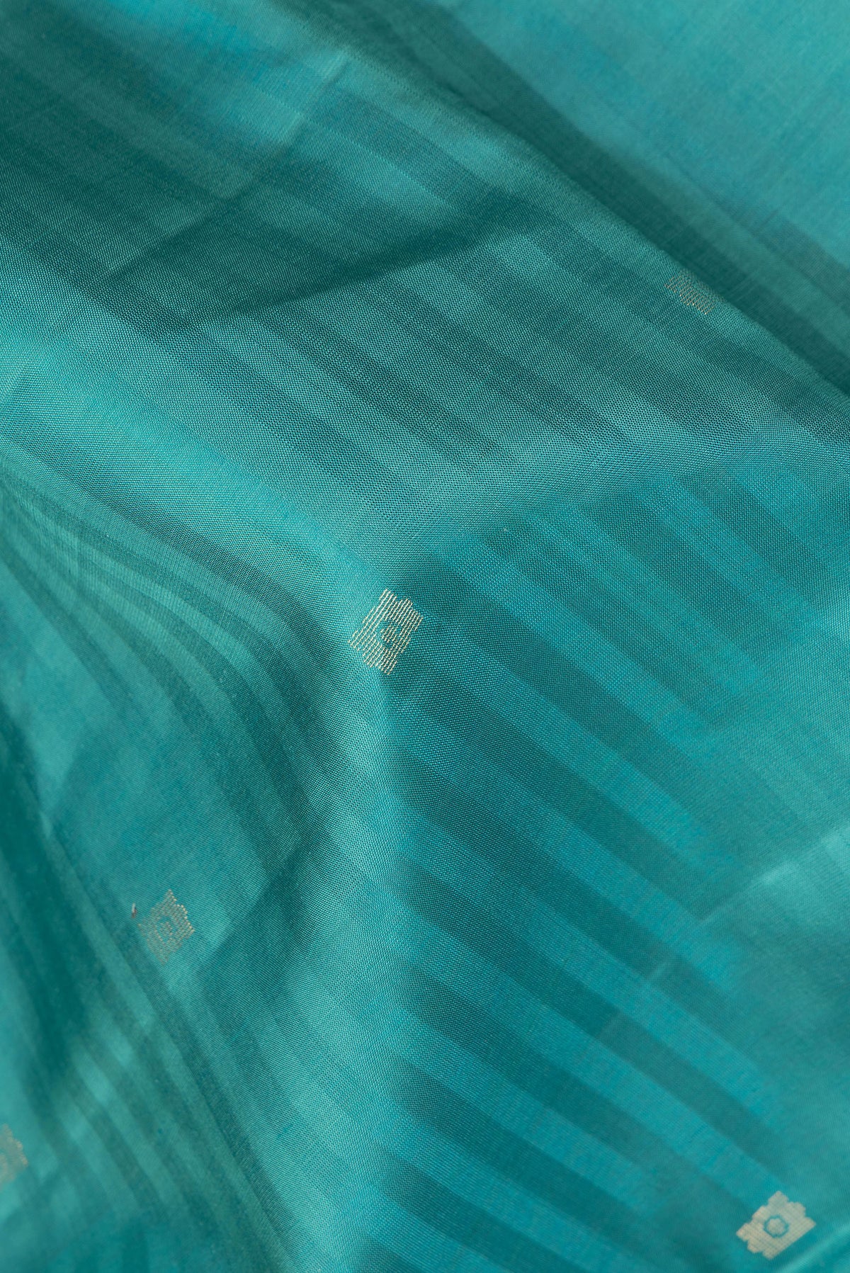 Close up of Pure Silk Peacock Blue Dual Tone Soft Saree with Zari Butta on the body and Fancy Border.  displaying folds