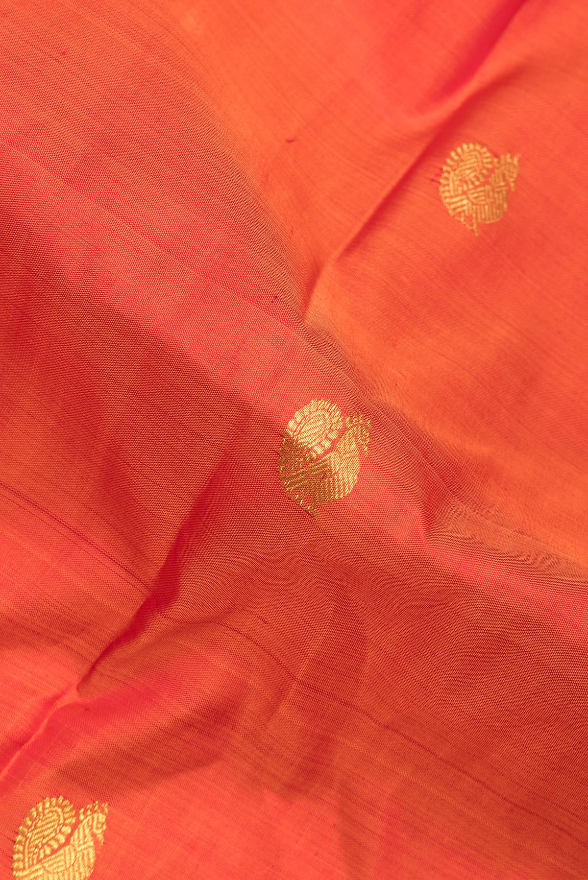 Close up of Pure Silk Orange Kanjivaram Saree with Zari Butta on the body and Zari Border.  displaying folds