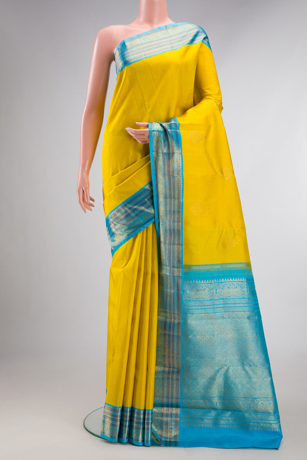 Pure Silk Yellow Kanjivaram Saree with Zari Butta on the body and Zari Border.  displayed on a mannequin