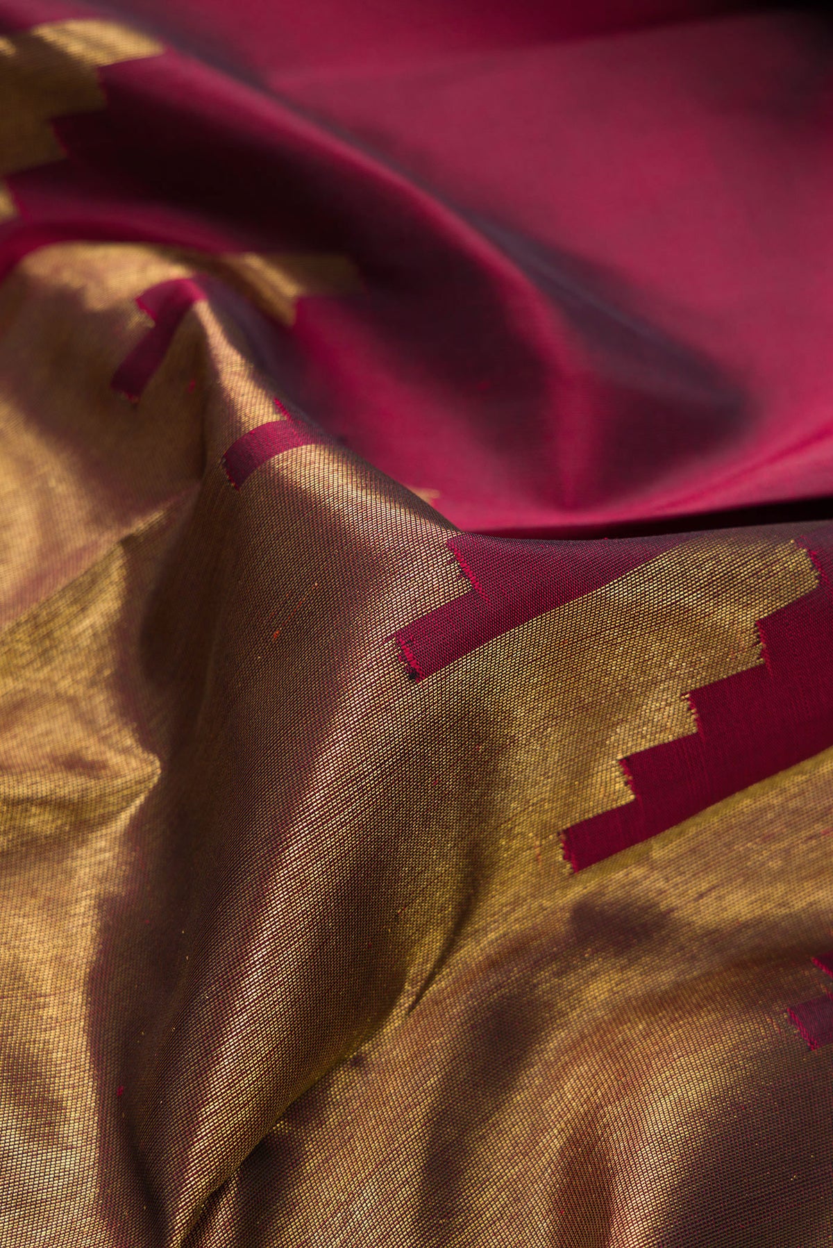 Close up of Pure Silk Pure Zari Maroon Dual Tone Kanjivaram Saree with Plain Body and Rising Temple Border.  displaying folds