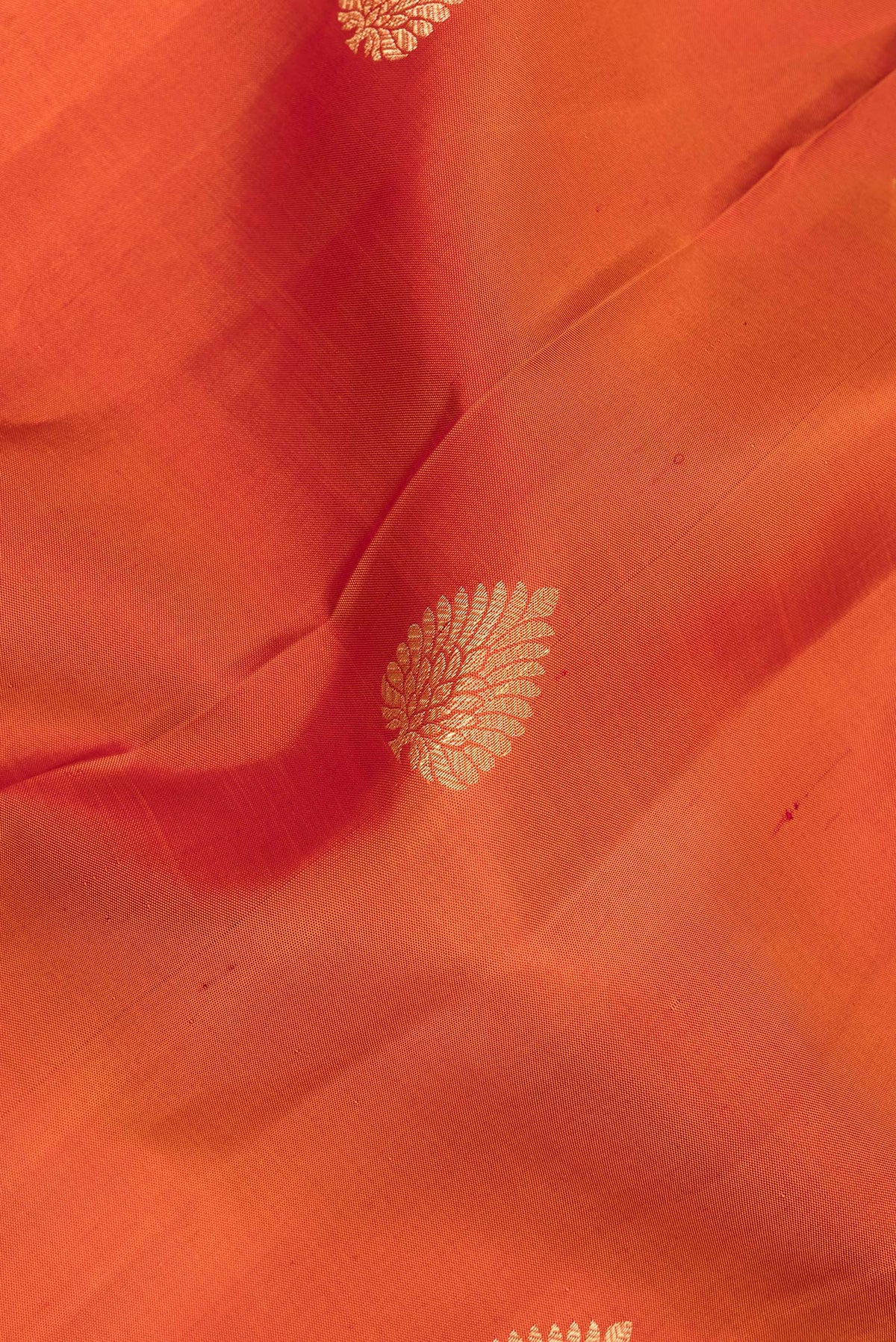 Close up of Pure Silk Orange Kanjivaram Saree with Zari Butta on the body and Zari And Thread Border.  displaying folds
