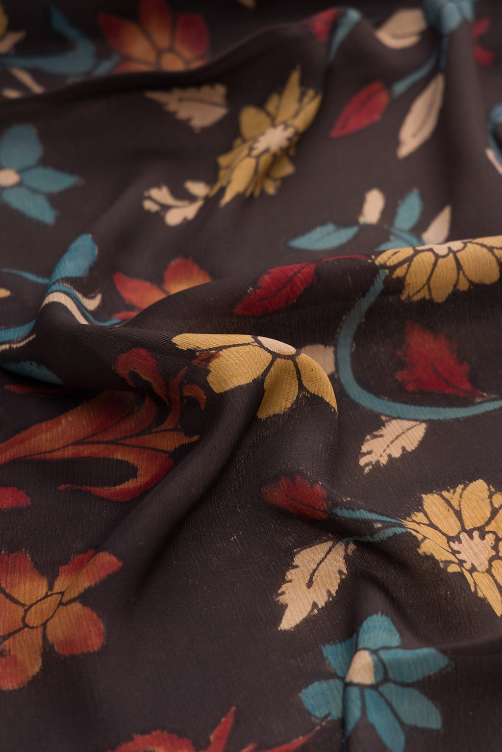 Close up of Brown Mysore Chiffon Saree with kalamkari Print on the body and Zari Border.  displaying folds