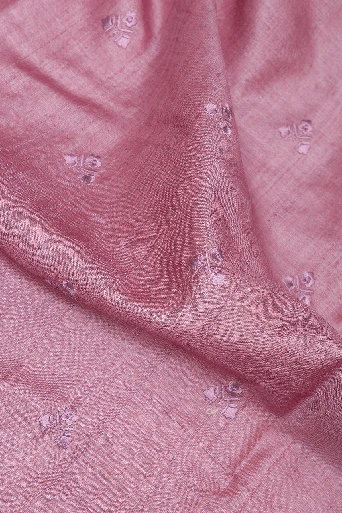Close up of Rose Gold Tussar Saree with Embroidery on the body and Embroidery Border.  displaying folds