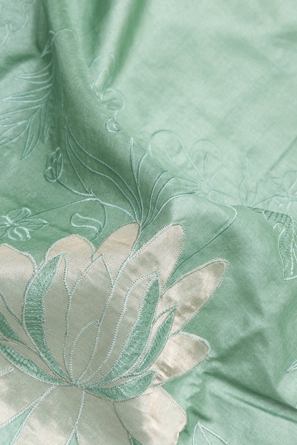 Close up of Pure Silk Mint Green Tussar Saree with Embroidery on the body and Embroidery Border.  displaying folds