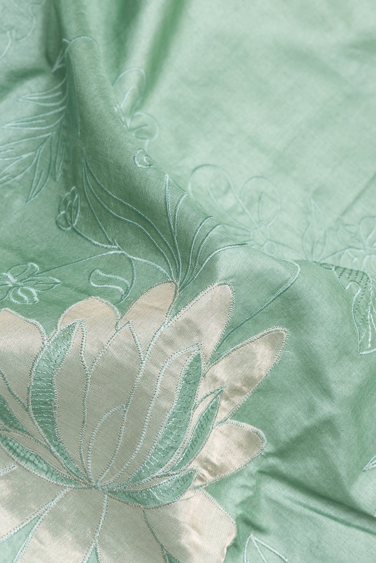 Close up of Pure Silk Mint Green Tussar Saree with Embroidery on the body and Embroidery Border.  displaying folds