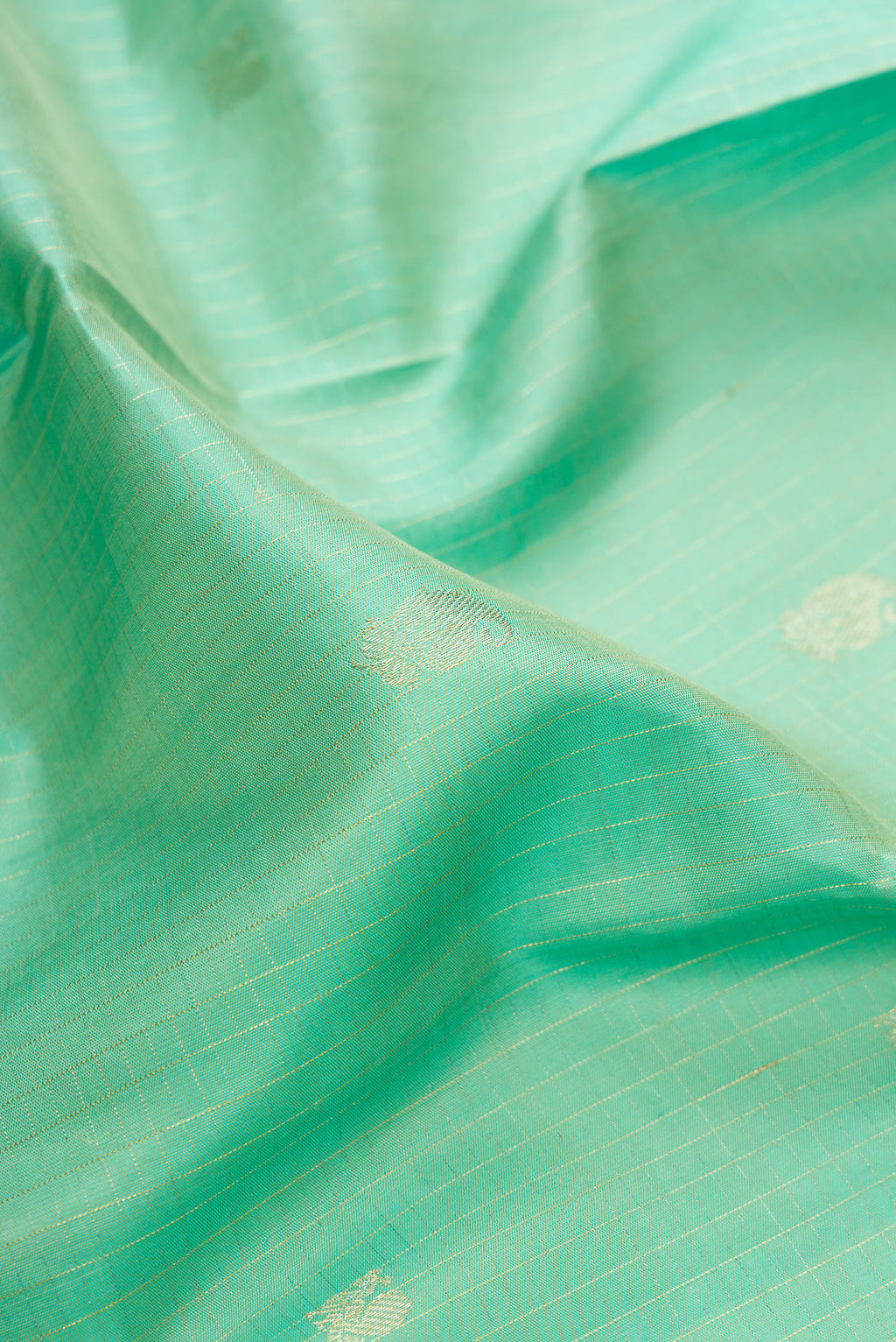 Close up of Pure Silk Sea Green Kanchipuram Saree with Zari Butta on the body and Fancy Border.  displaying folds