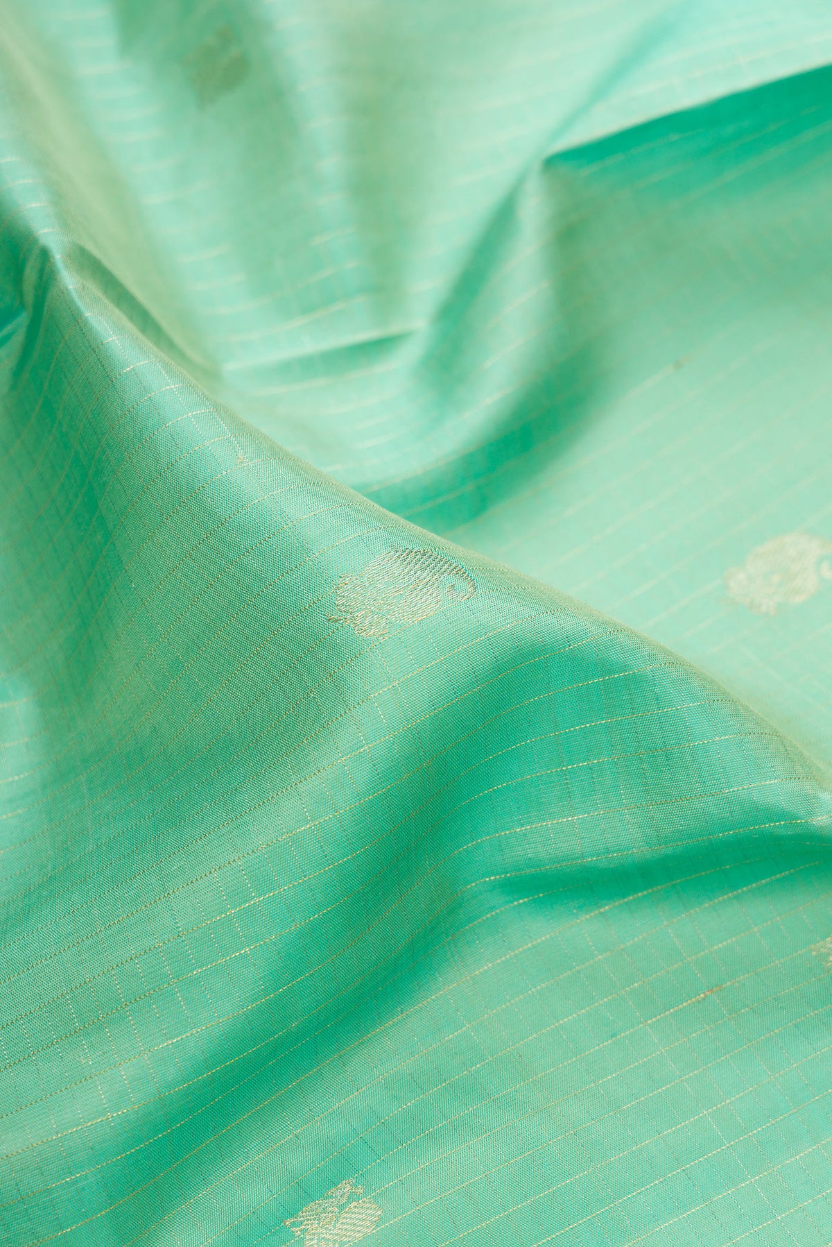 Close up of Pure Silk Sea Green Kanchipuram Saree with Zari Butta on the body and Fancy Border.  displaying folds