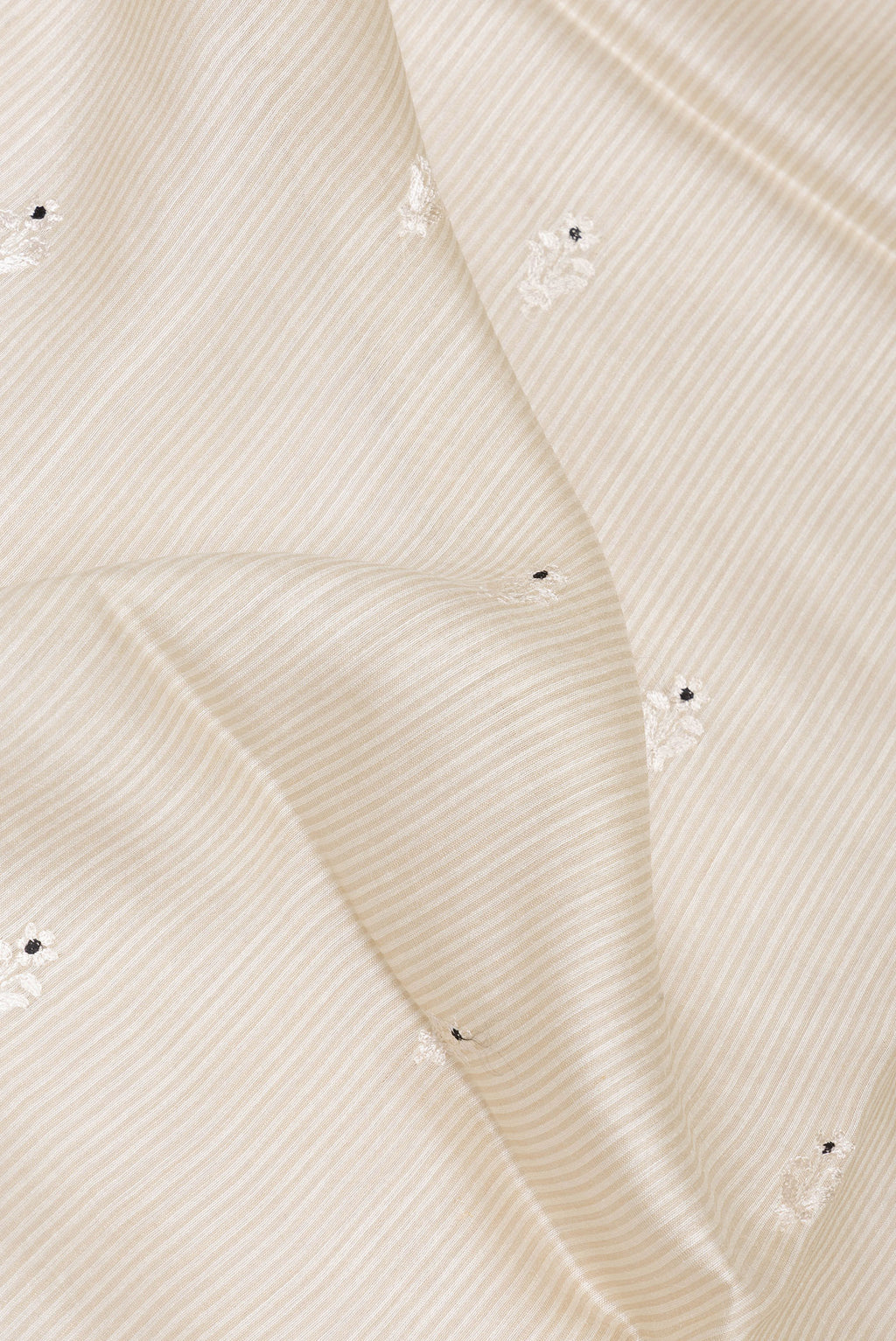 Close up of Cream Tussar Saree with Embroidery on the body and Embroidery Border.  displaying folds