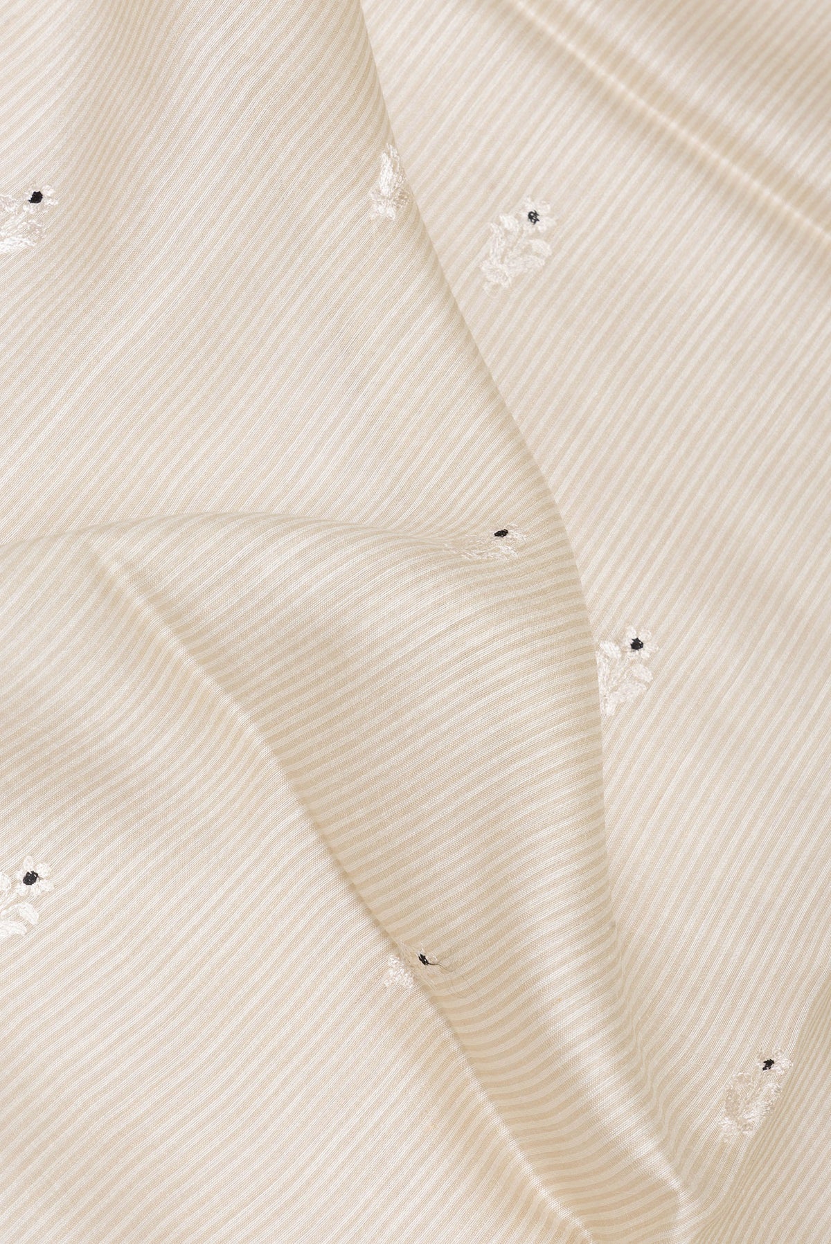 Close up of Cream Tussar Saree with Embroidery on the body and Embroidery Border.  displaying folds