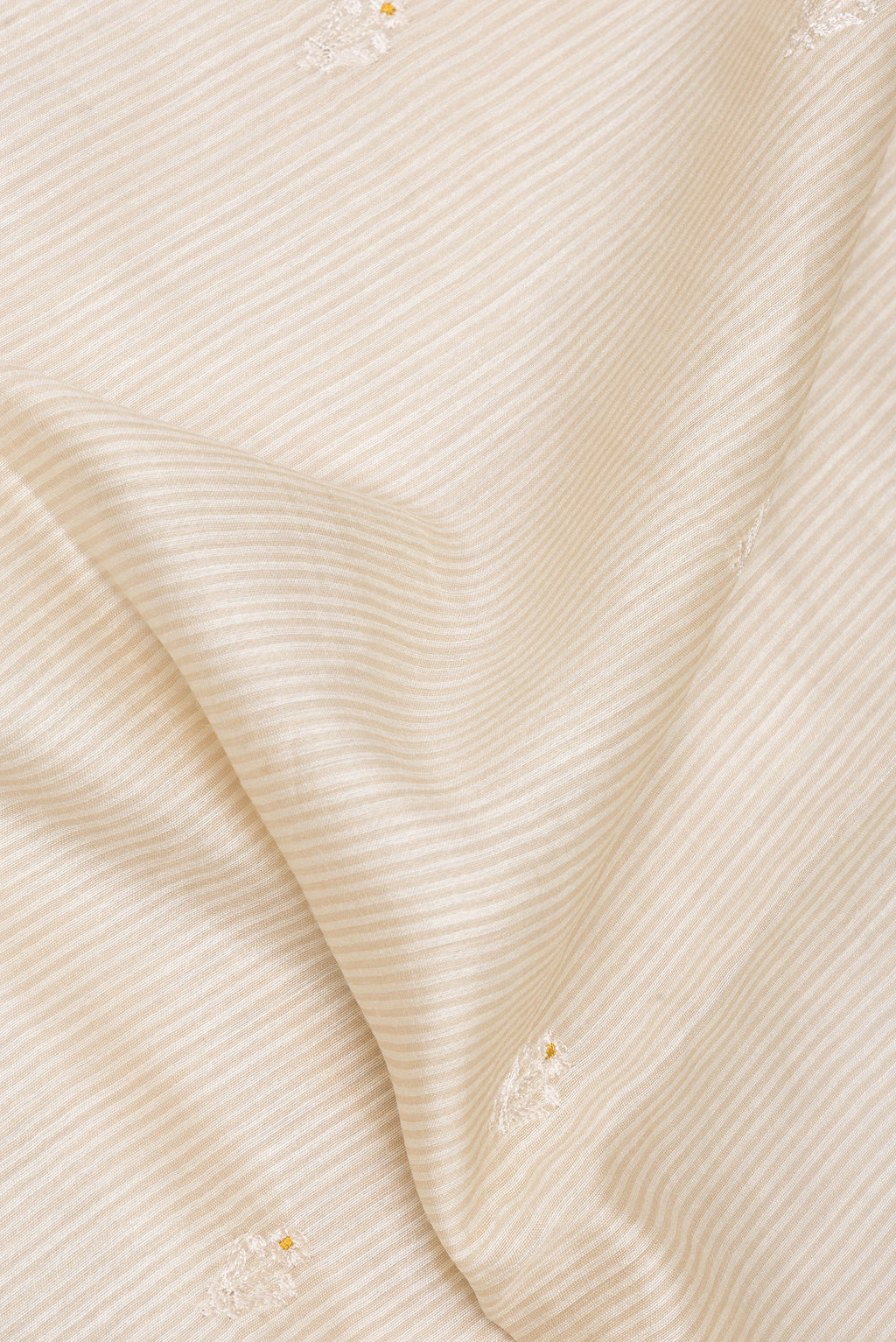Close up of Cream Tussar Saree with Embroidery on the body and Embroidery Border.  displaying folds