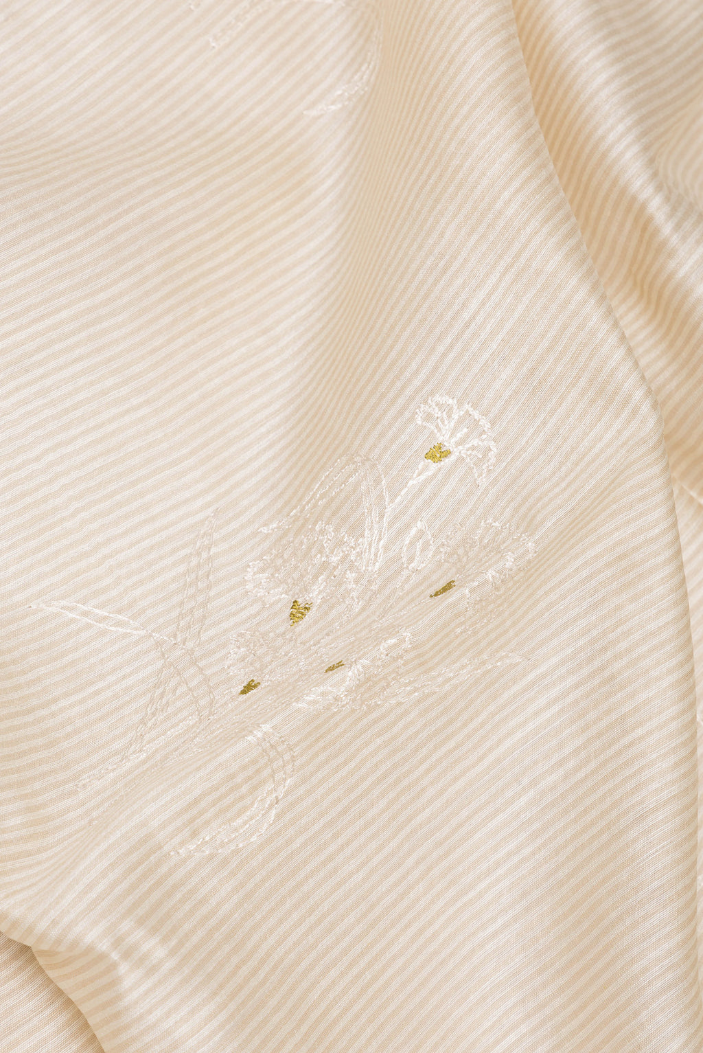 Close up of Cream Tussar Saree with Embroidery on the body and Embroidery Border.  displaying folds