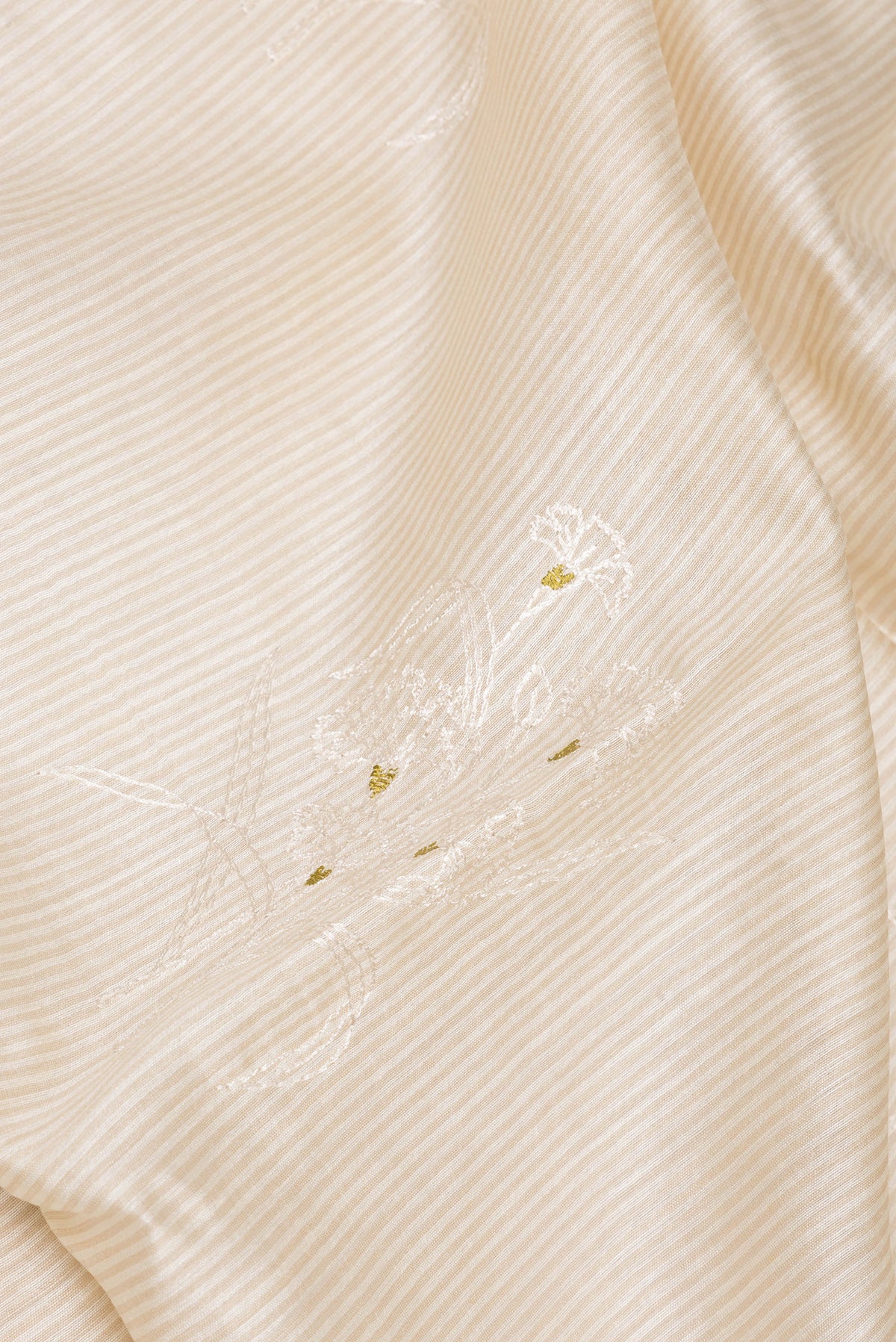 Close up of Cream Tussar Saree with Embroidery on the body and Embroidery Border.  displaying folds