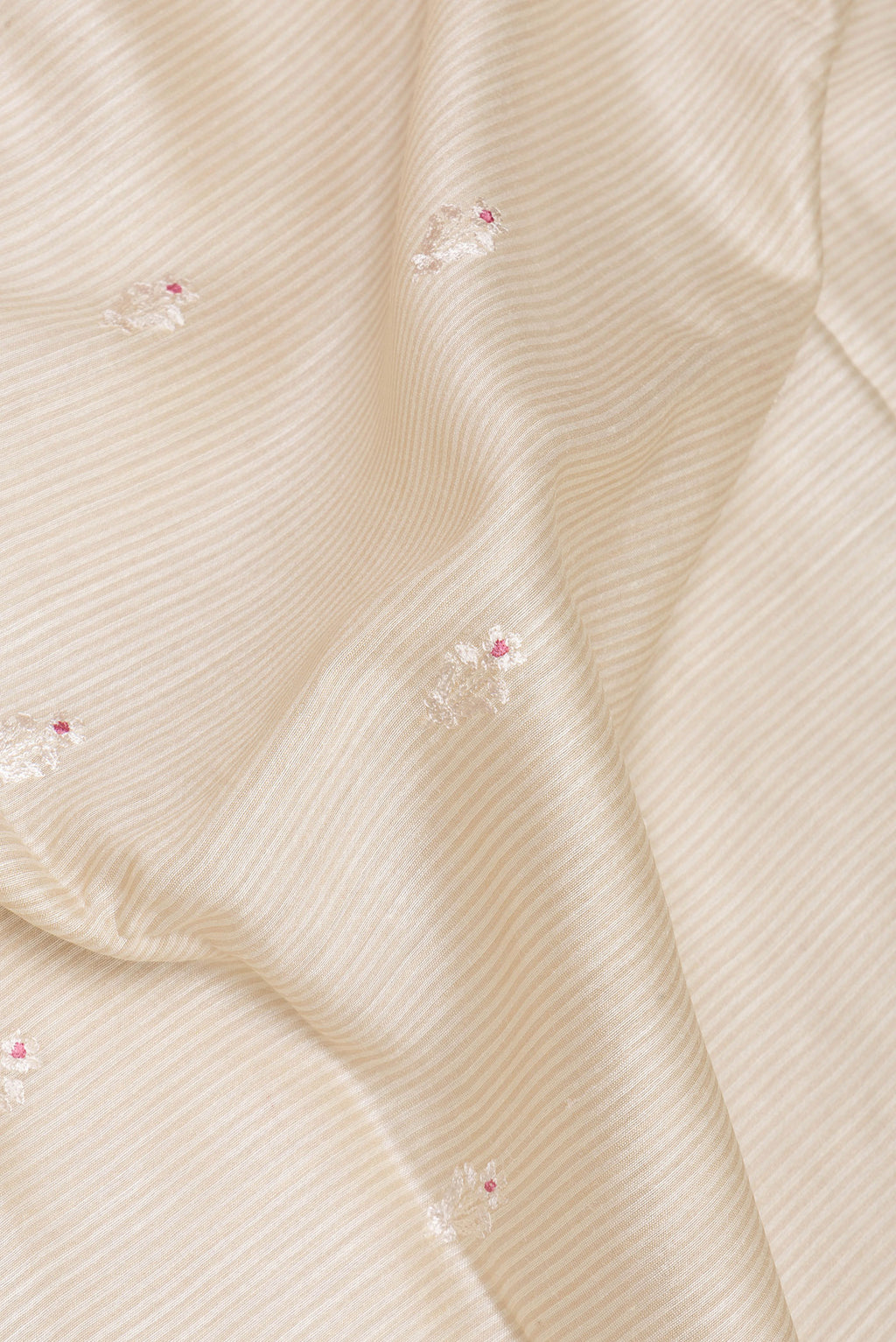 Close up of Cream Tussar Saree with Embroidery on the body and Embroidery Border.  displaying folds