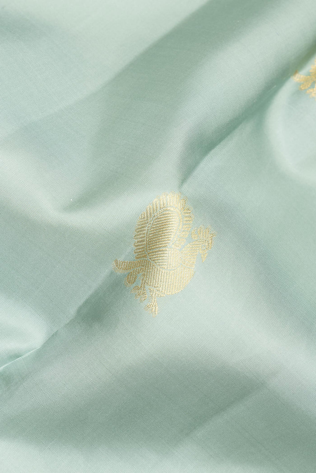 Close up of Pure Silk Sea Green Kanchipuram Saree with Zari Butta on the body and Zari Border.  displaying folds