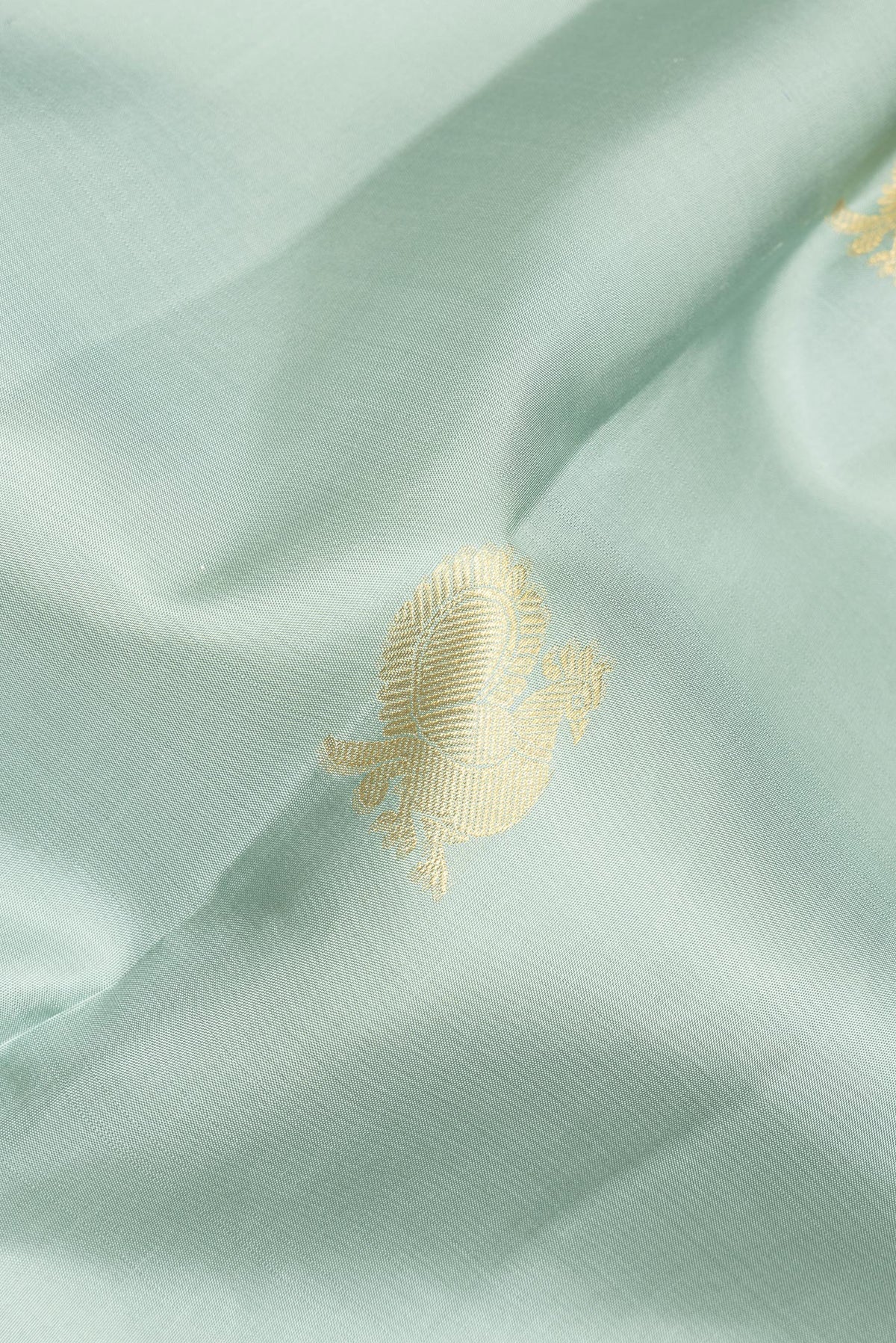 Close up of Pure Silk Sea Green Kanchipuram Saree with Zari Butta on the body and Zari Border.  displaying folds