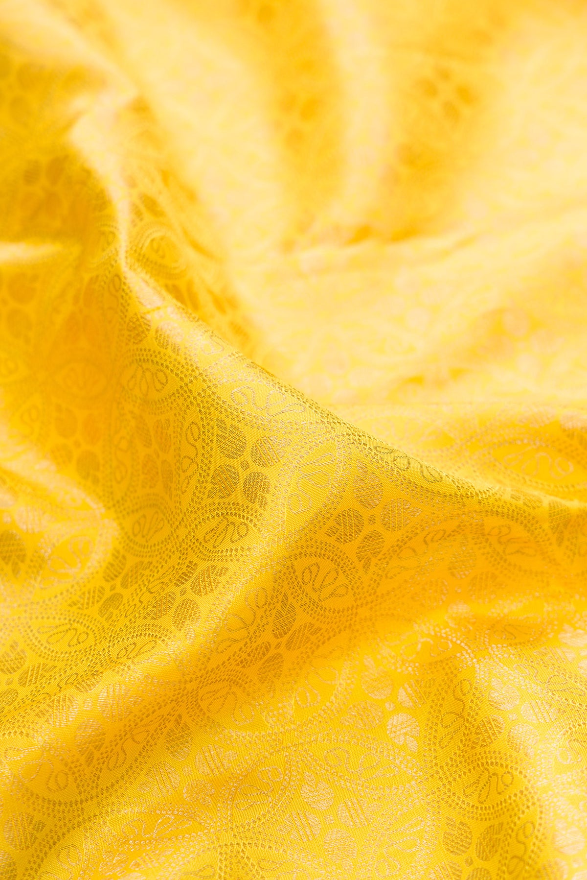 Close up of Pure Silk Lemon Yellow Kanchipuram Saree with Zari Brocade on the body and Fancy Border.  displaying folds