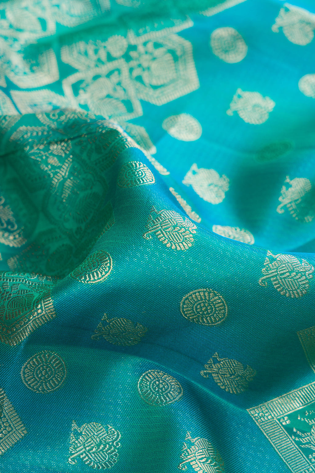 Close up of Pure Silk Blue and Sea Green Color Kanjivaram Saree with Zari Brocade on the body and Fancy Border.  displaying folds