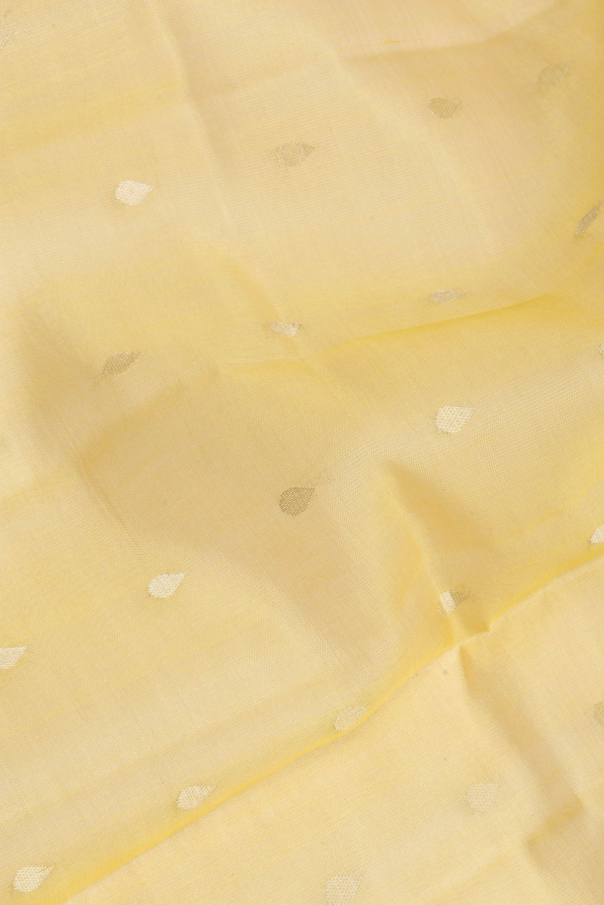 Close up of Pure Silk Yellow Dual Tone Tussar Saree with Zari Butta on the body and Zari Border.  displaying folds