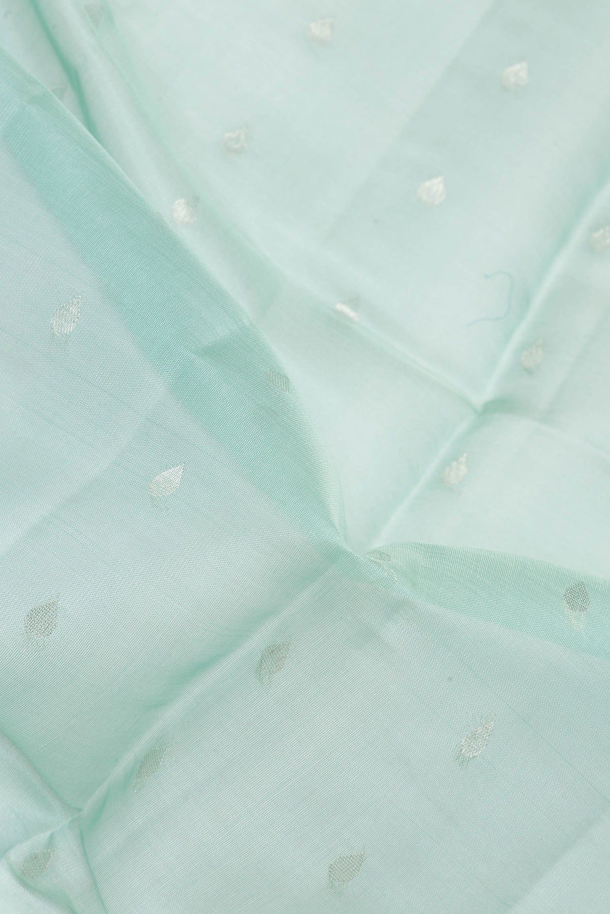 Close up of Light Blue Tussar Saree with Zari Butta on the body and Zari Border.  displaying folds