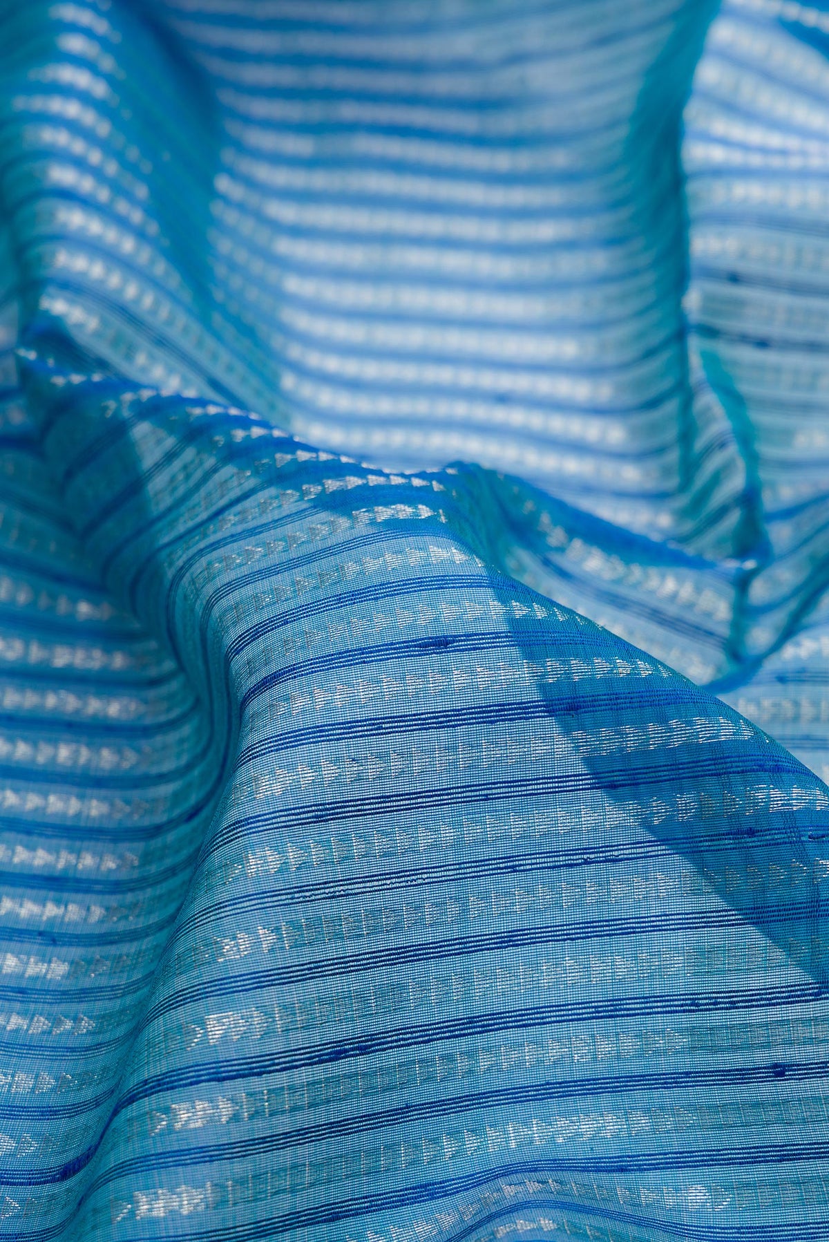 Close up of Peacock Blue Tussar Saree with Stripes on the body and Zari Border.  displaying folds