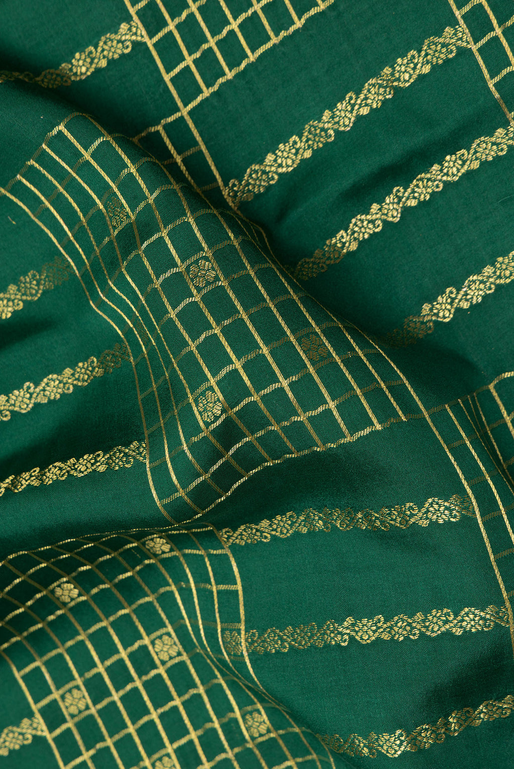 Close up of Bottle Green Mysore Crepe Saree with Checked design on the body and Zari Border.  displaying folds