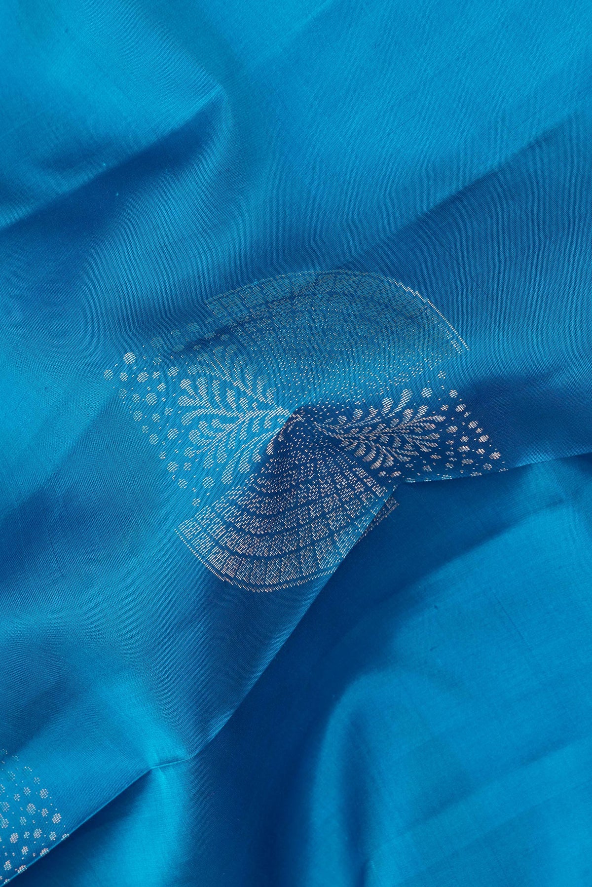 Close up of Pure Silk Peacock Blue Dual Tone Soft Saree with Zari Butta on the body and Without Border.  displaying folds