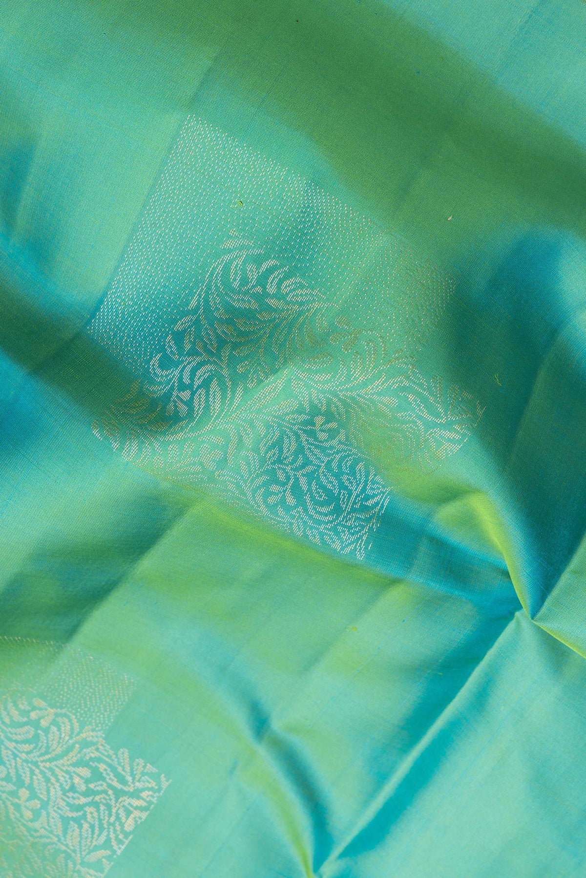 Close up of Pure Silk Green Dual Tone Soft Saree with Zari Butta on the body and Without Border.  displaying folds