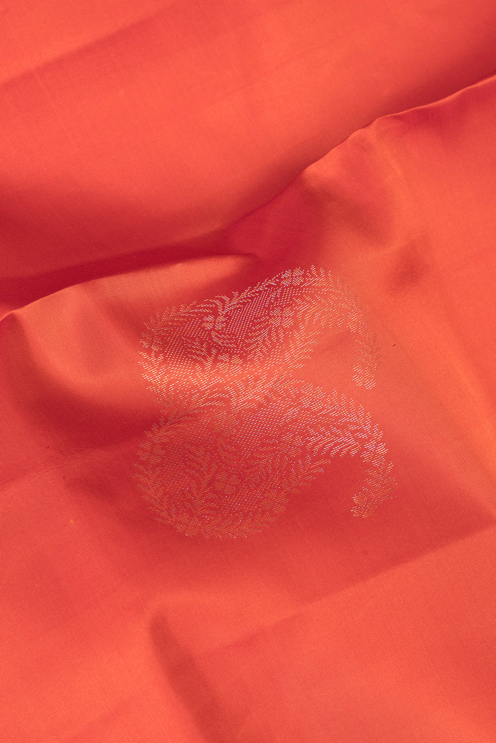 Close up of Pure Silk Brick Orange Dual Tone Soft Saree with Zari Butta on the body and Without Border.  displaying folds