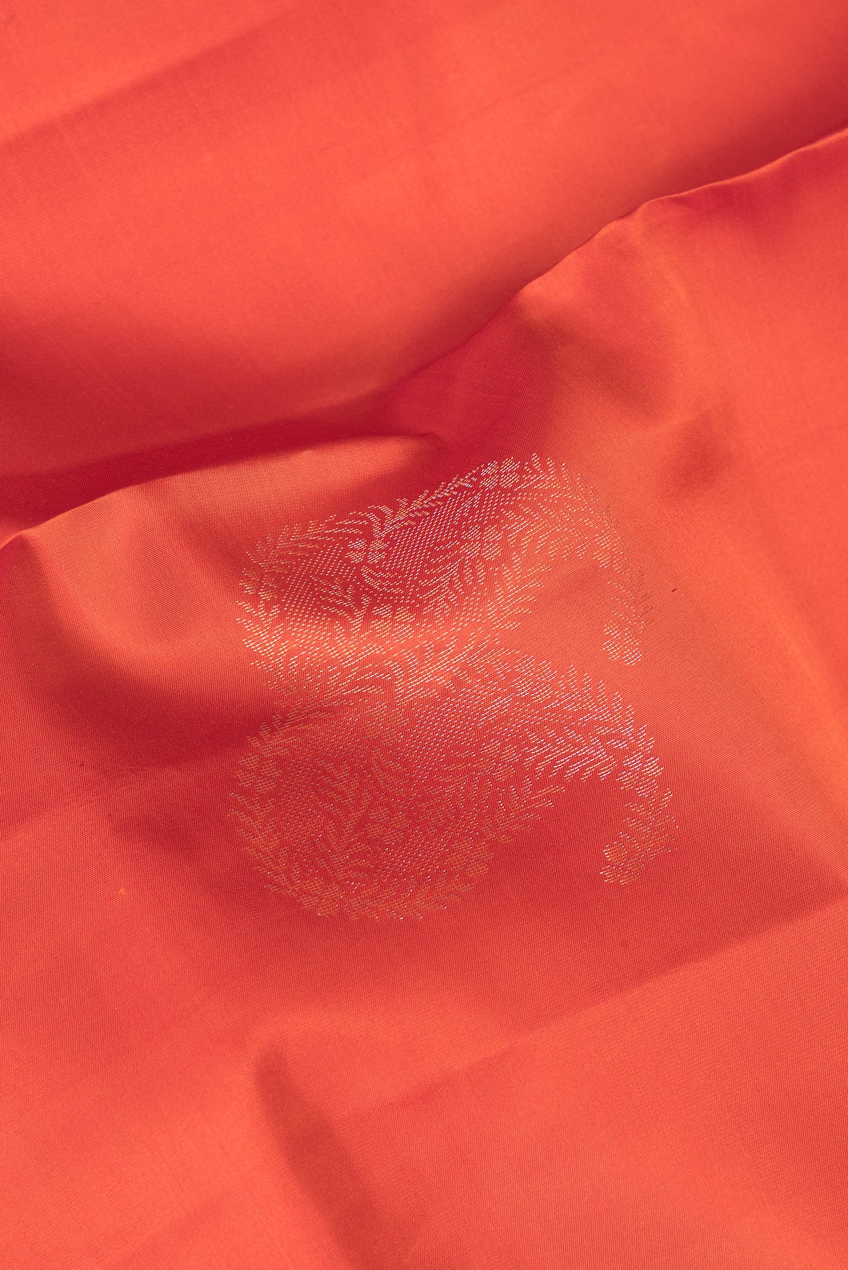 Close up of Pure Silk Brick Orange Dual Tone Soft Saree with Zari Butta on the body and Without Border.  displaying folds