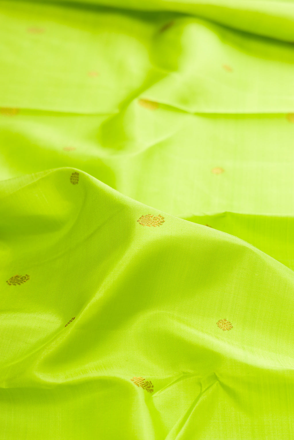 Close up of Pure Silk Parrot Green Kanchipuram Saree with Zari Butta on the body and Zari Border.  displaying folds
