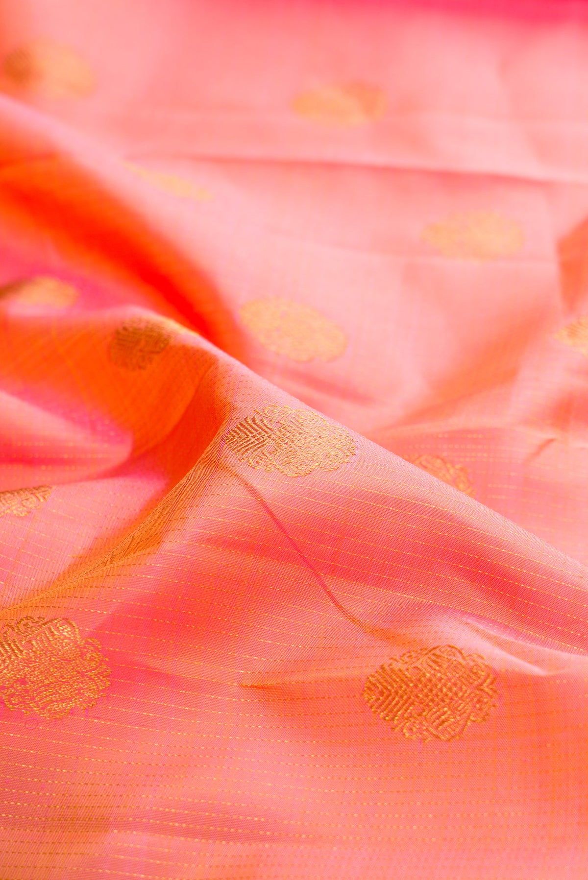 Close up of Pure Silk Peach Kanchipuram Saree with Zari Butta on the body and Temple Border.  displaying folds