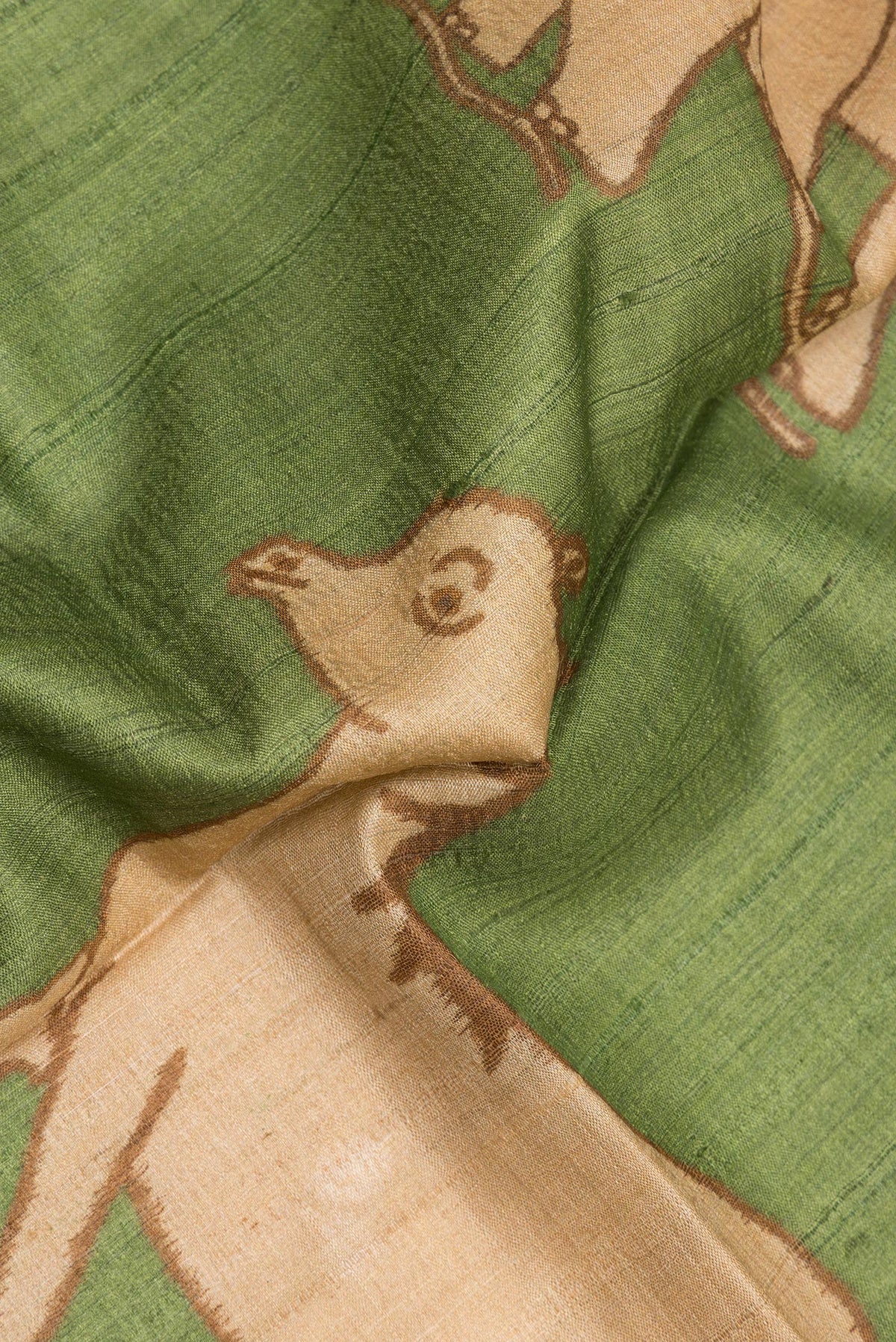 Close up of Mehandi Green Tussar Saree with Printed design on the body and Zari Border.  displaying folds