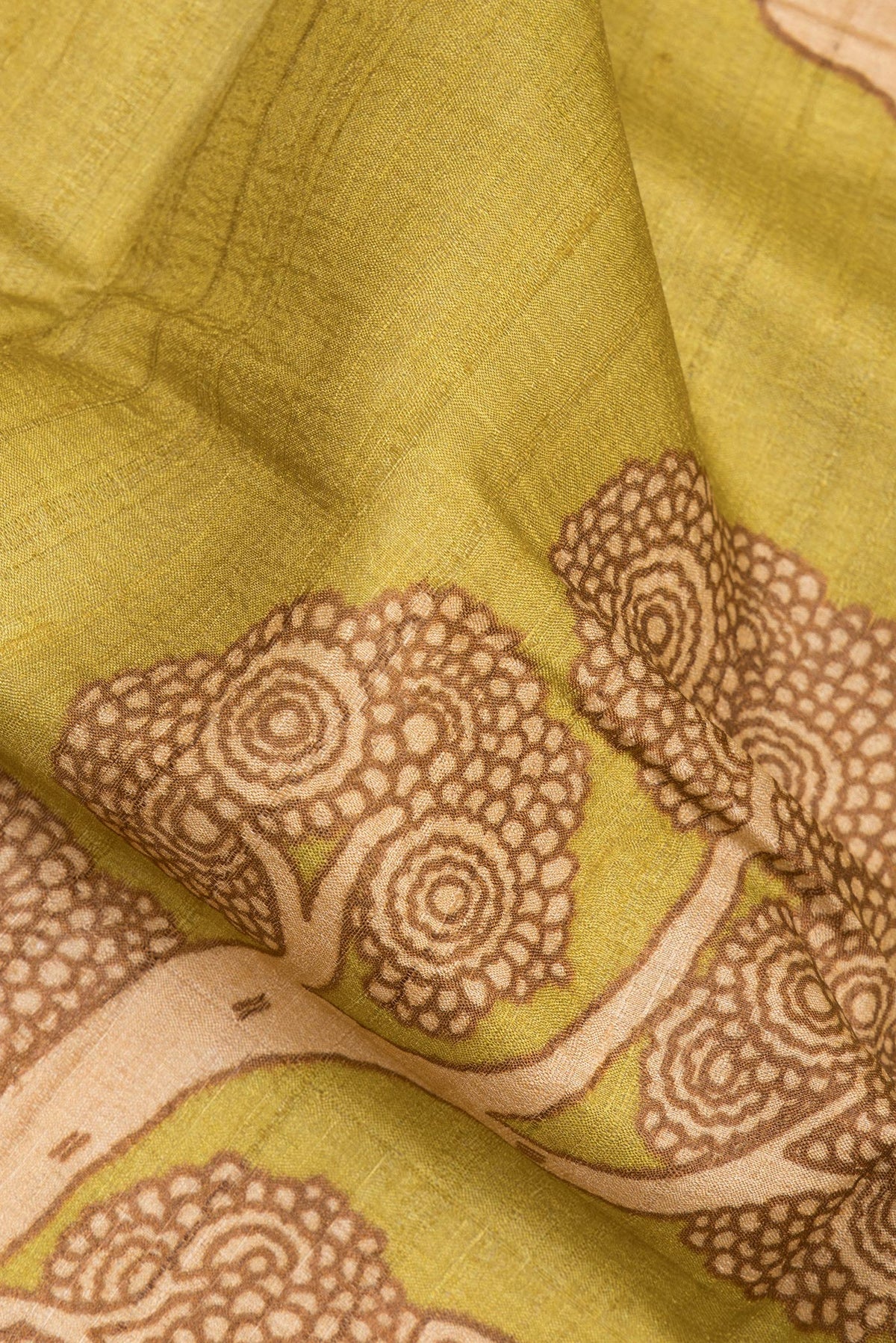 Close up of Pure Silk Mustard Tussar Saree with Printed design on the body and Zari Border.  displaying folds
