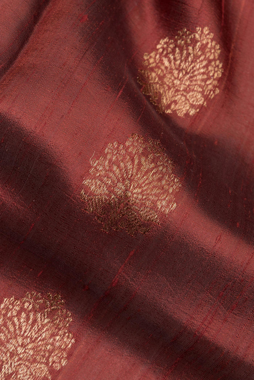 Close up of Brown Dual Tone Raw Saree with Zari Butta on the body and Zari Border.  displaying folds