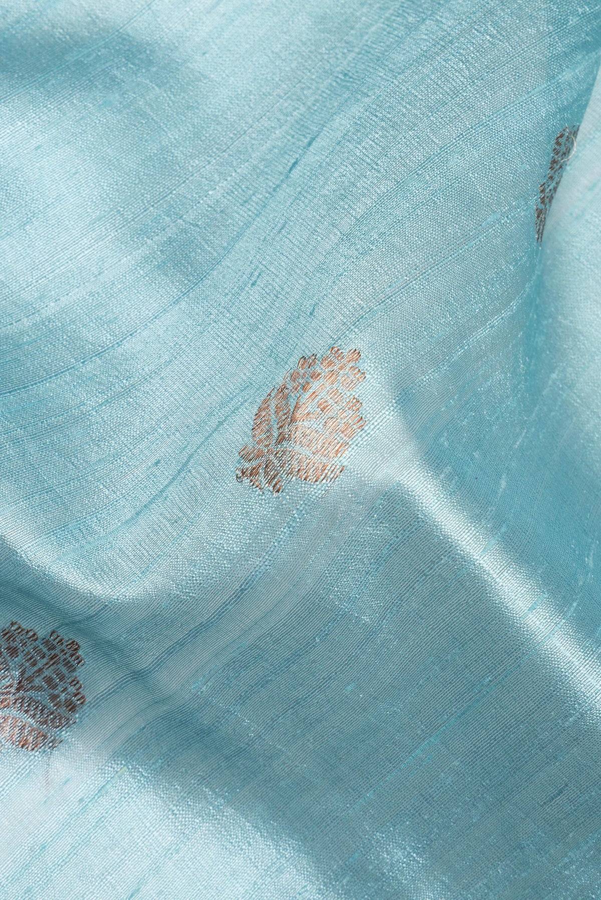 Close up of Light Blue Raw Saree with Zari Butta on the body and Zari Border.  displaying folds