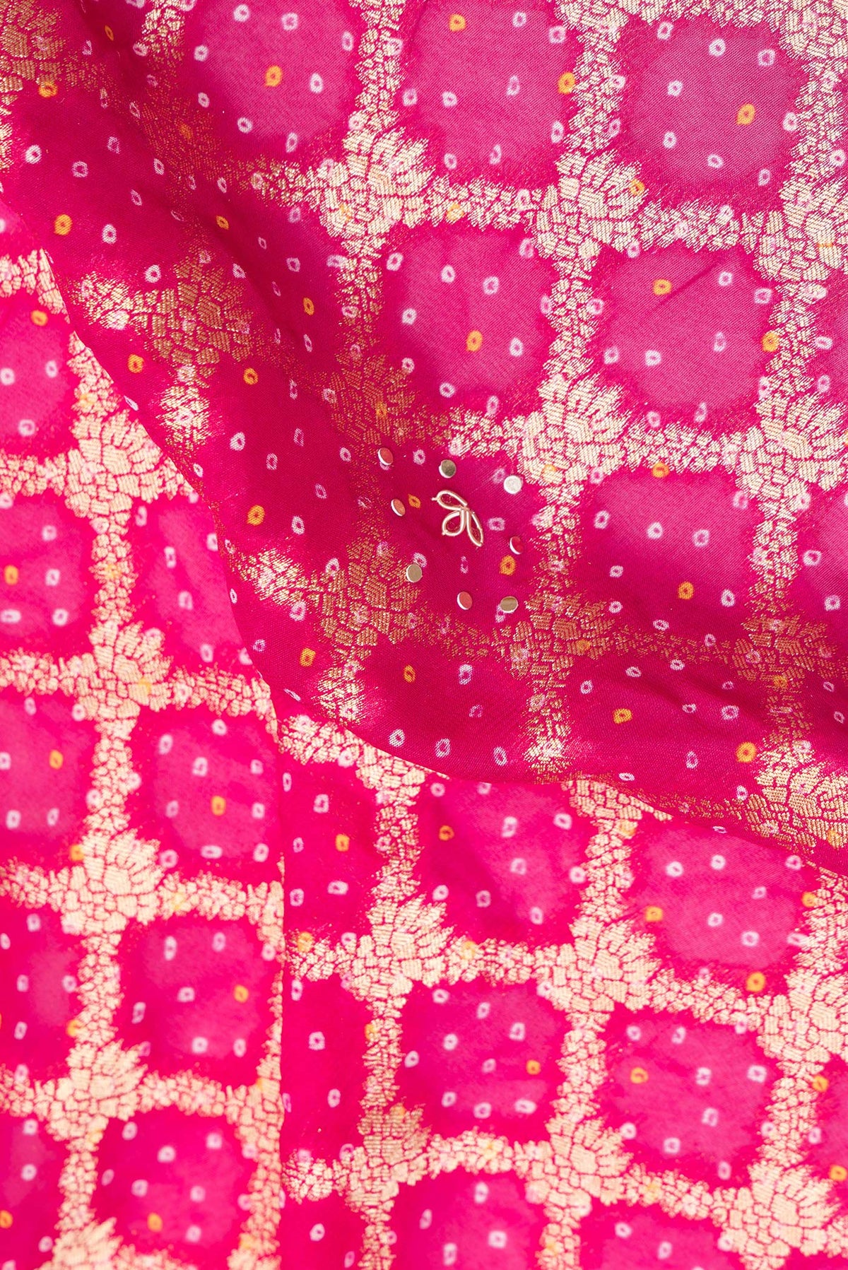 Close up of Pink and Lavender Color Banarasi Georgette Saree with Bandhani Print on the body and Embroidered Border.  displaying folds