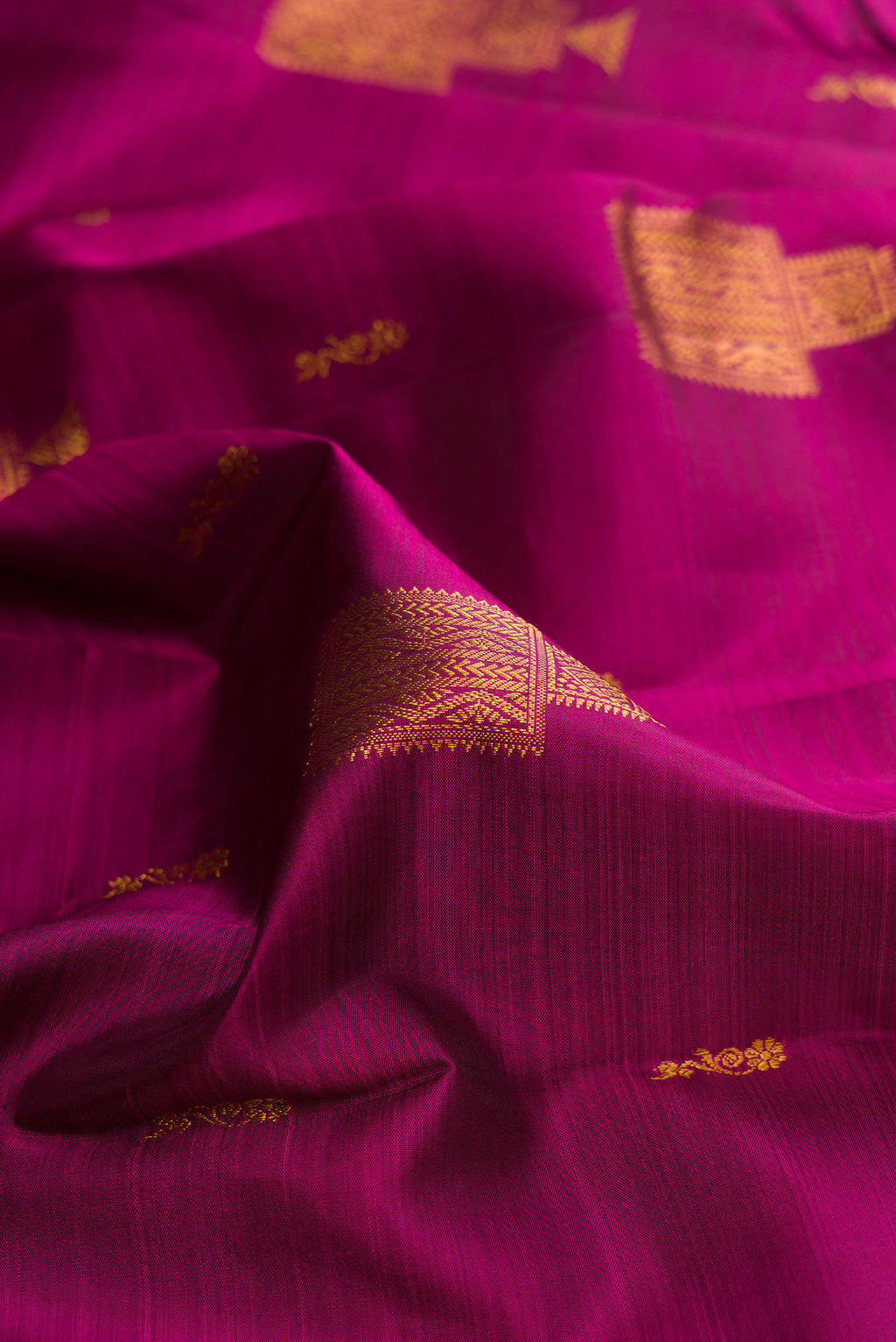Close up of Pure Silk Magenta Kanjivaram Saree with Zari Butta on the body and Zari Border.  displaying folds