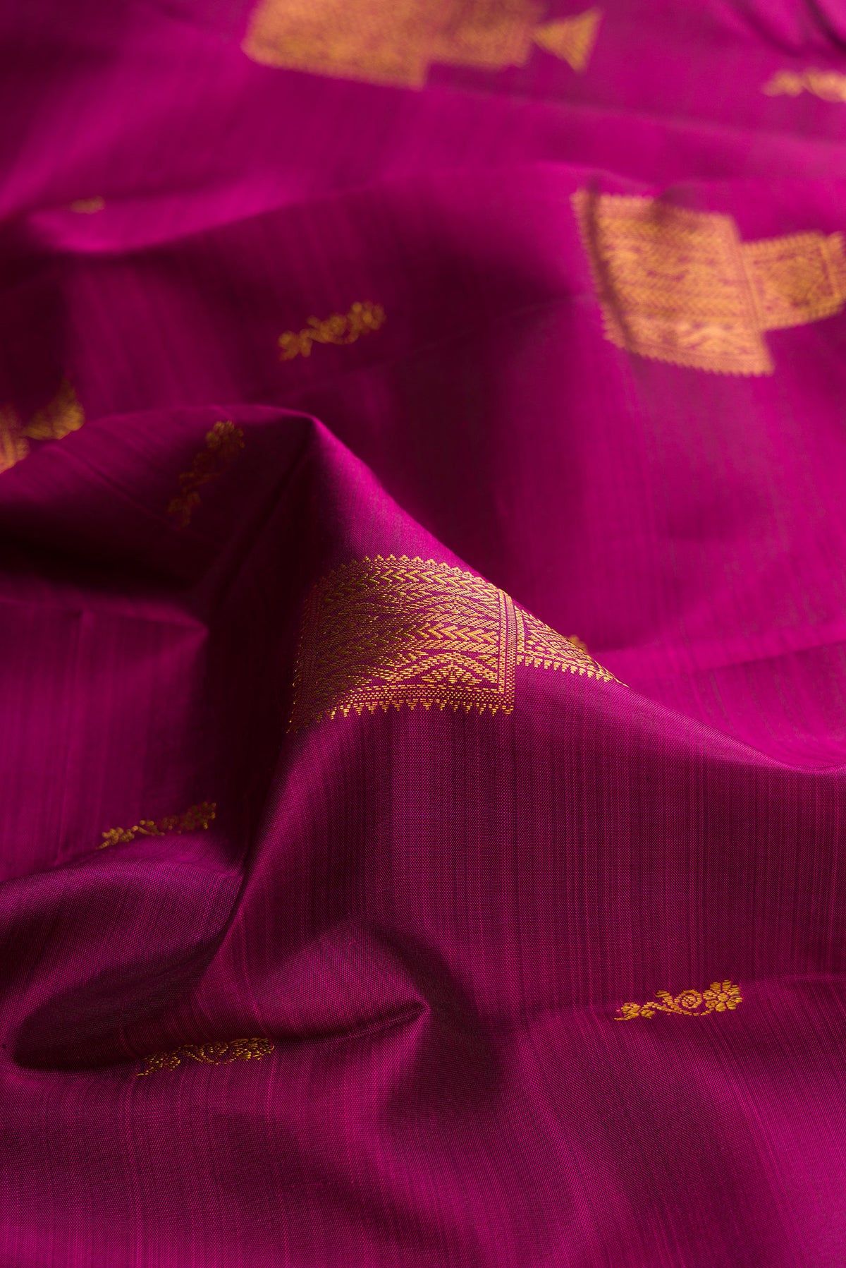 Close up of Pure Silk Magenta Kanjivaram Saree with Zari Butta on the body and Zari Border.  displaying folds