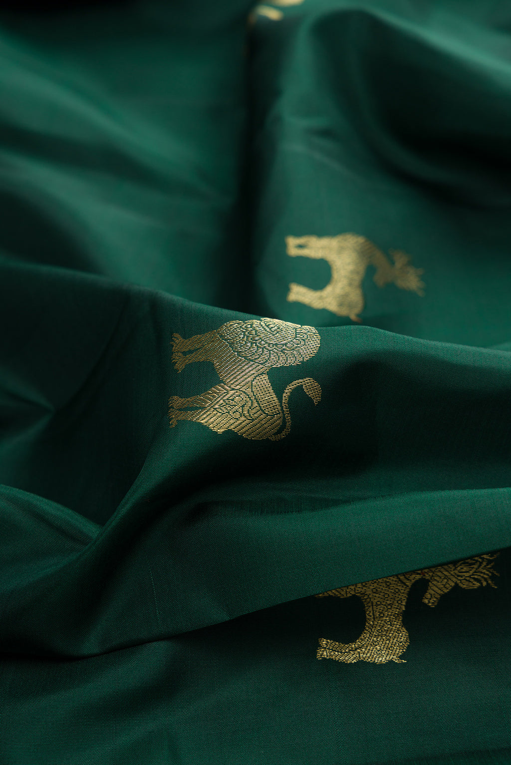 Close up of Pure Silk Bottle Green Kanjivaram Saree with Zari Butta on the body and Zari Border.  displaying folds