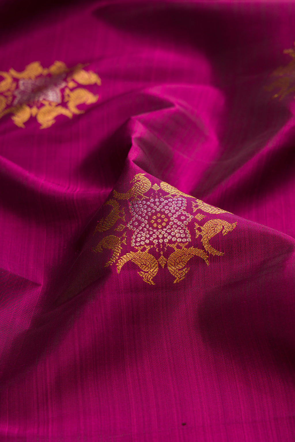 Close up of Pure Silk Magenta Kanjivaram Saree with Zari Butta on the body and Zari Border.  displaying folds